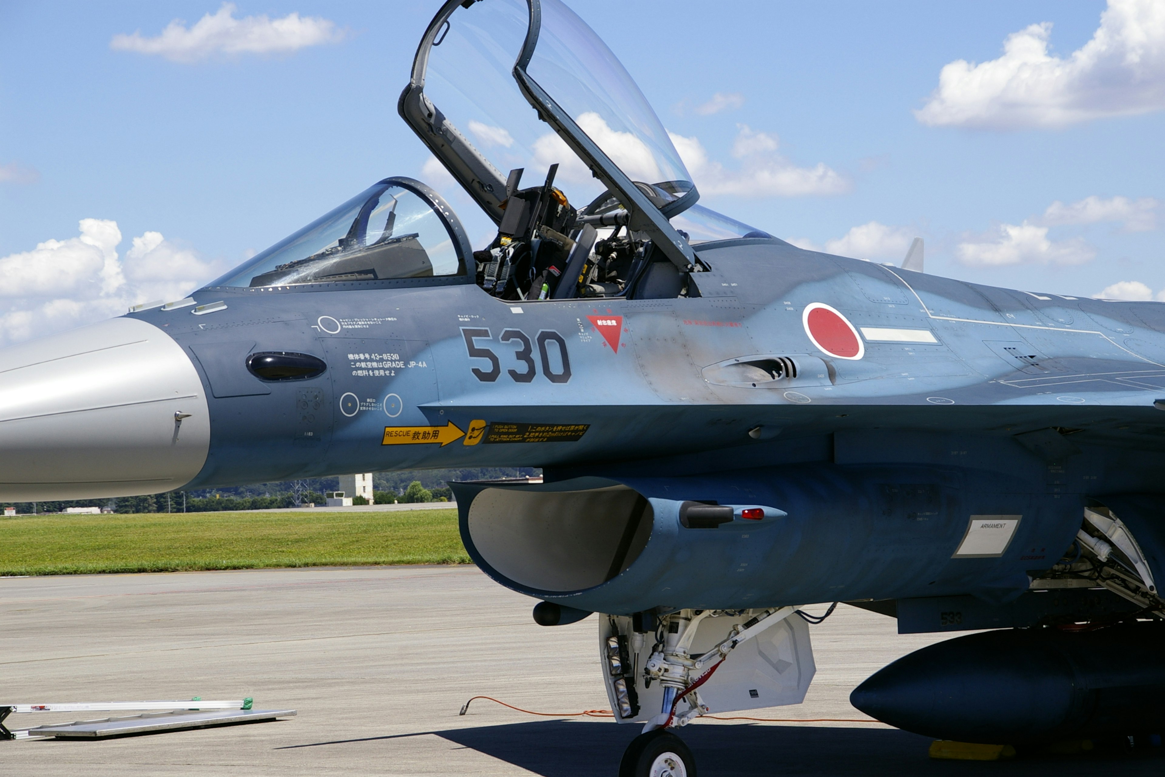 Seitenansicht eines Kampfjets mit offenem Cockpit und japanischen Markierungen