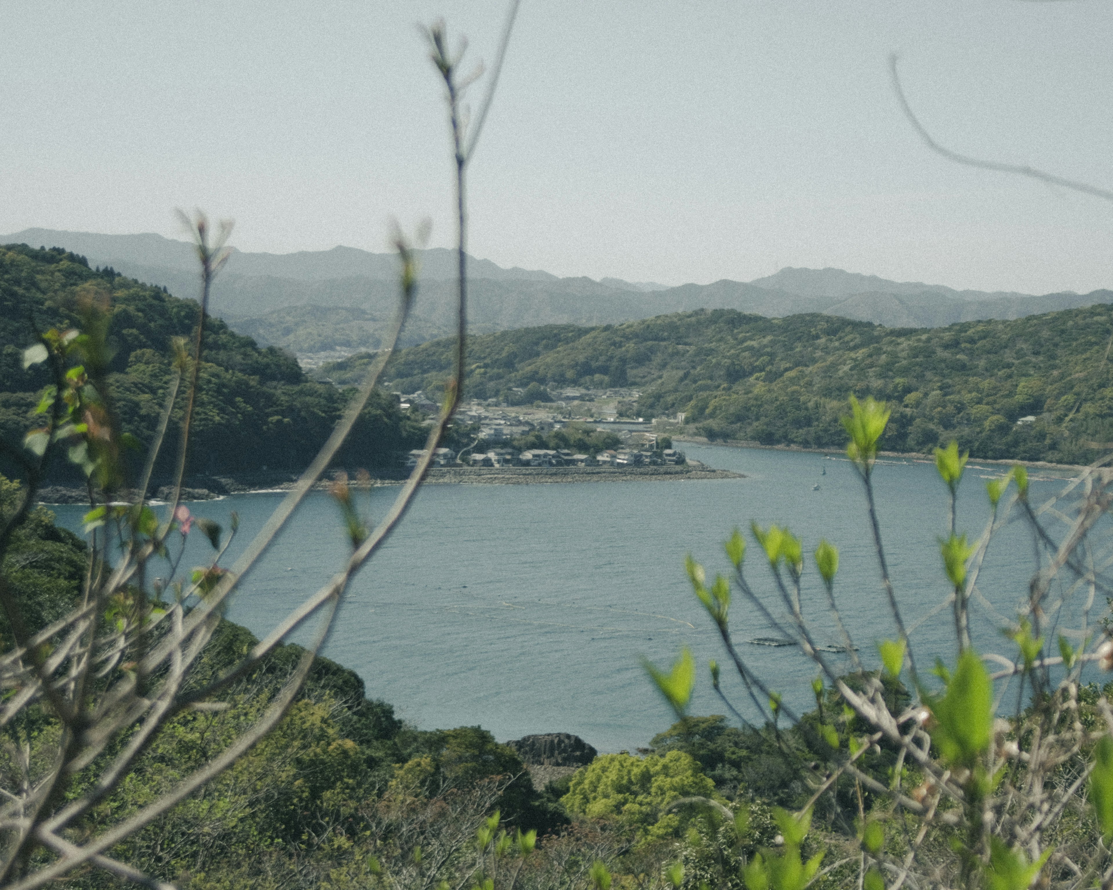 Una vista serena di un piccolo villaggio circondato da colline lussureggianti e acque calme