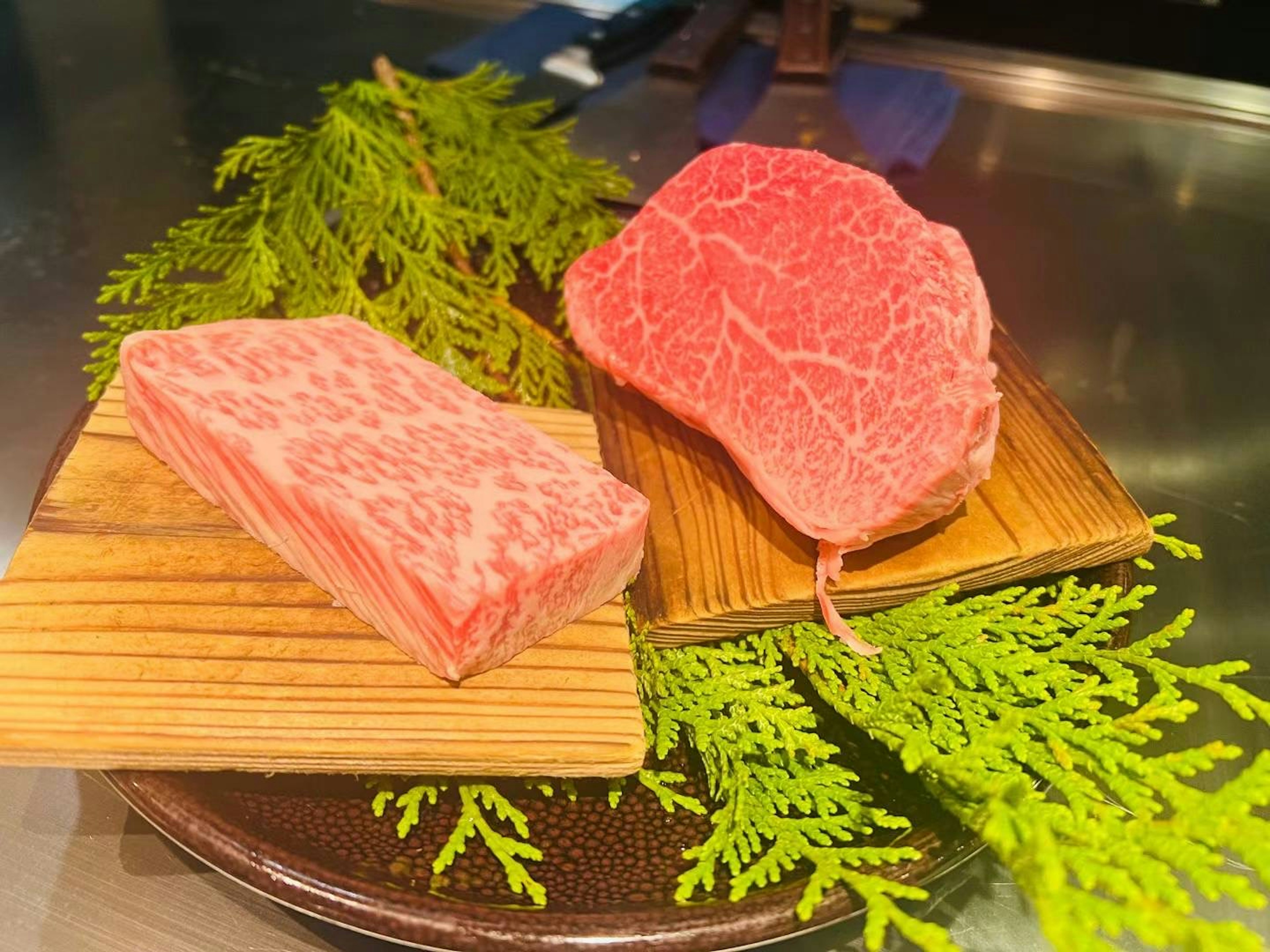 Hermosa carne de wagyu veteada presentada sobre tablas de madera con hojas verdes