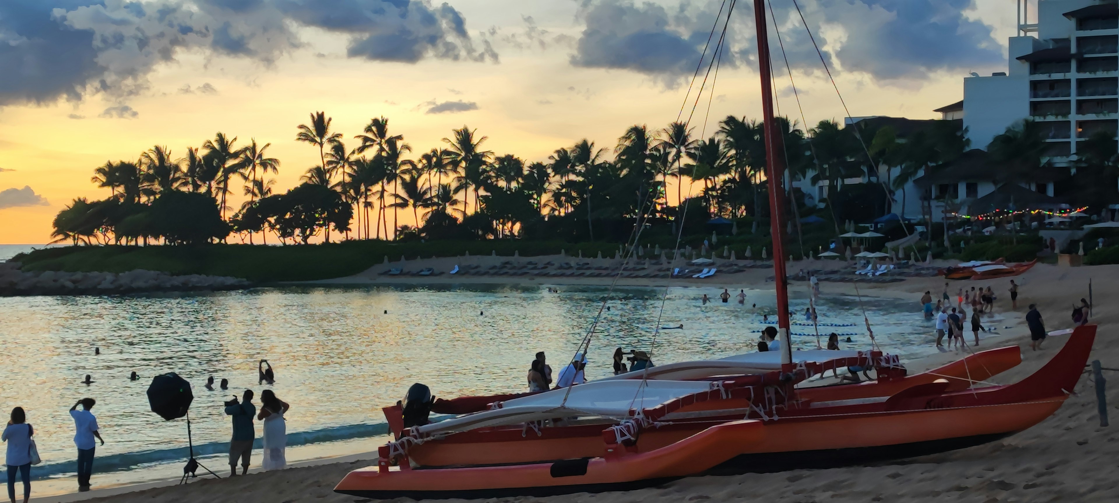 Canoë orange sur la plage avec des gens au coucher du soleil