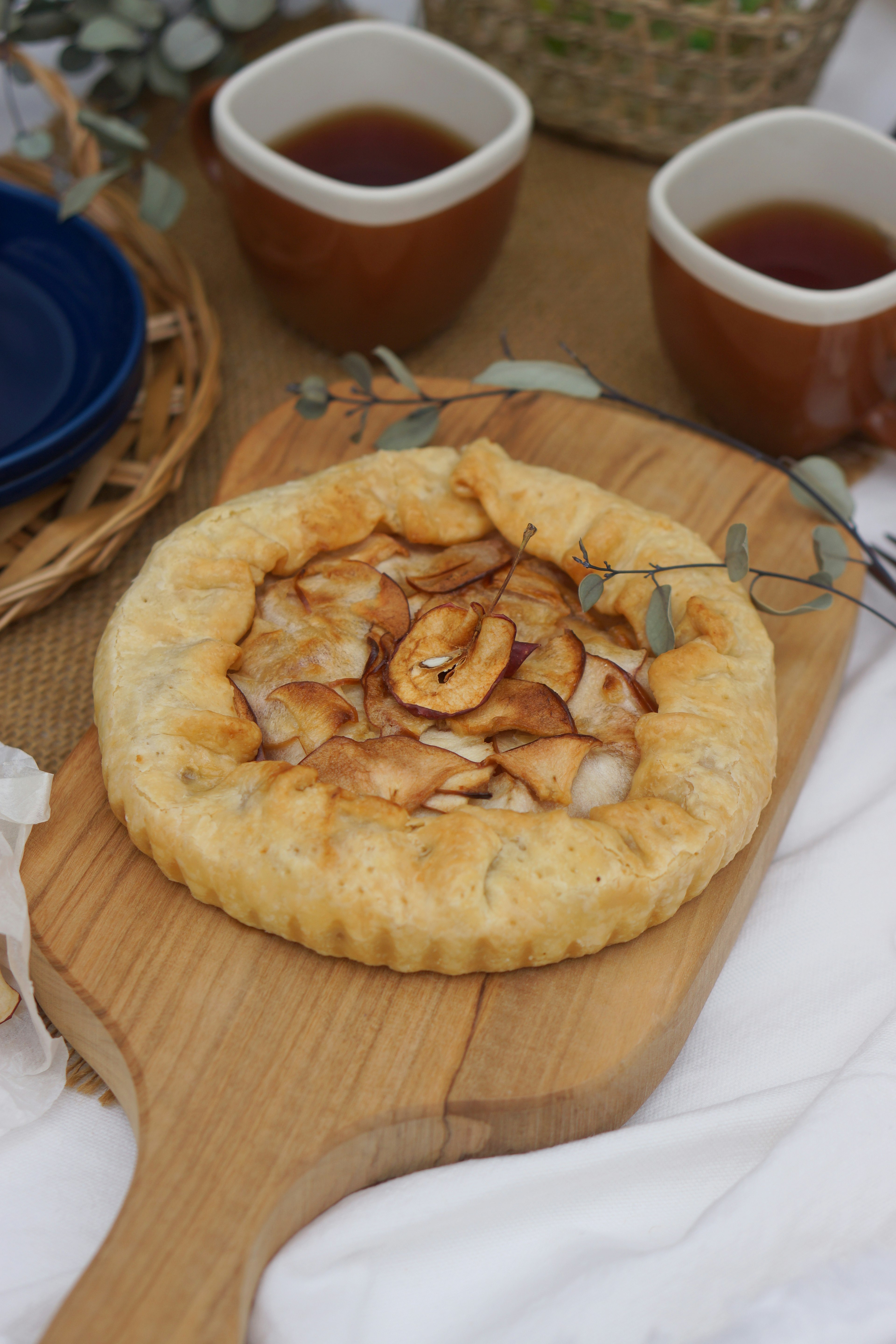 Tarta de frutas recién horneada sobre una tabla de madera con dos tazas de té cercanas