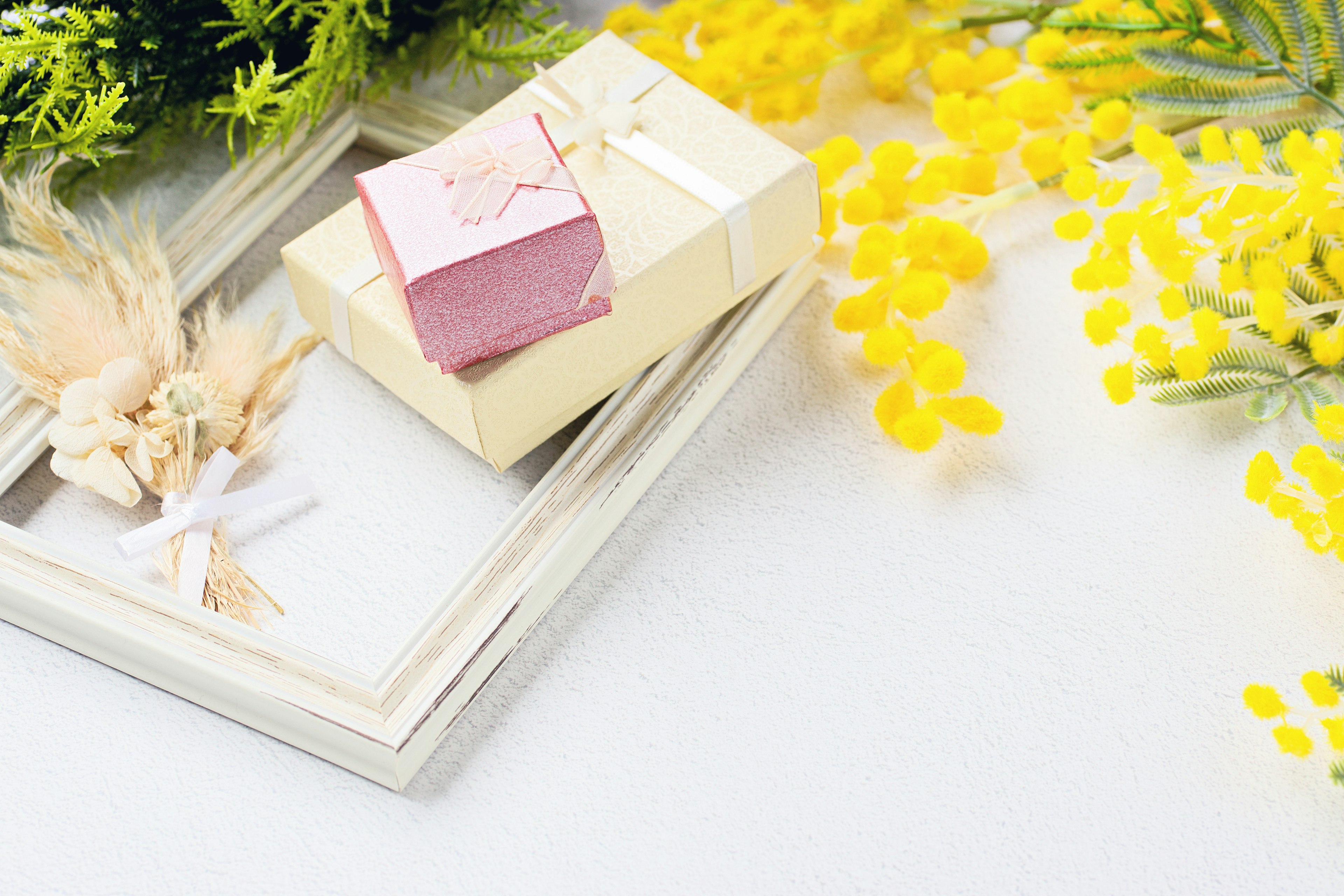 Gift box and frames surrounded by yellow flowers and decorative leaves