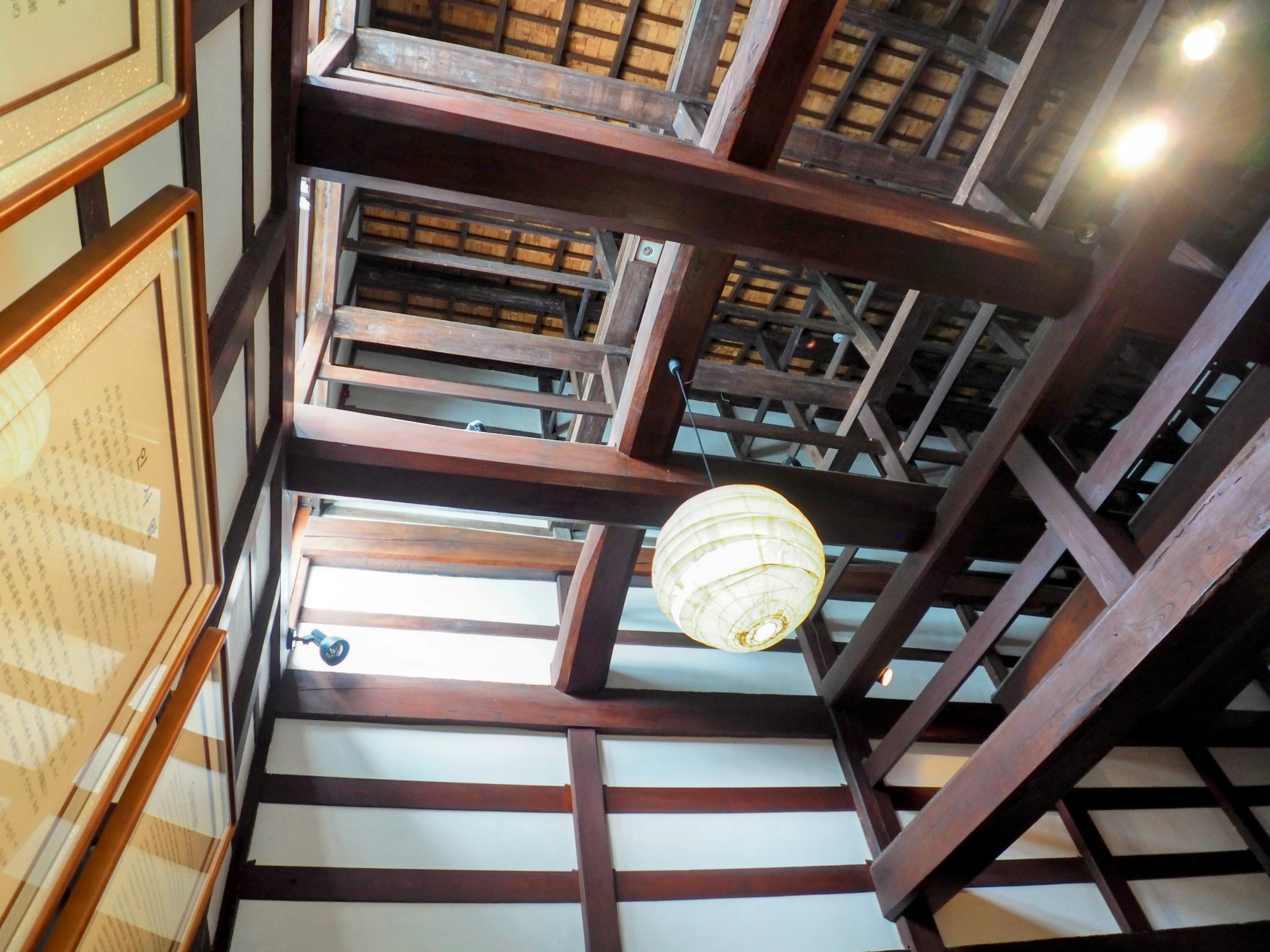 Angle of a ceiling featuring wooden beams and traditional lighting