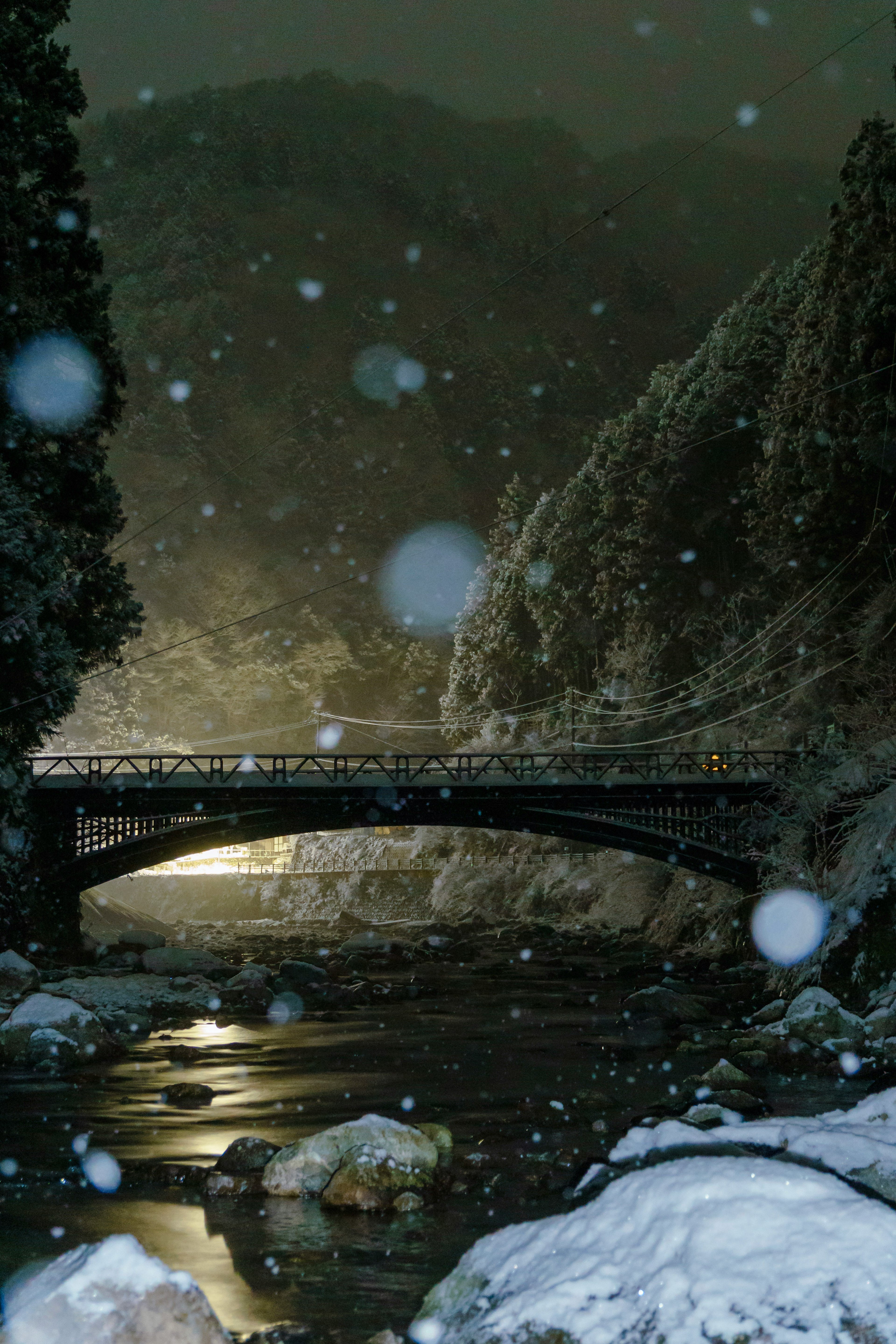 Snow-covered bridge and tranquil river at night