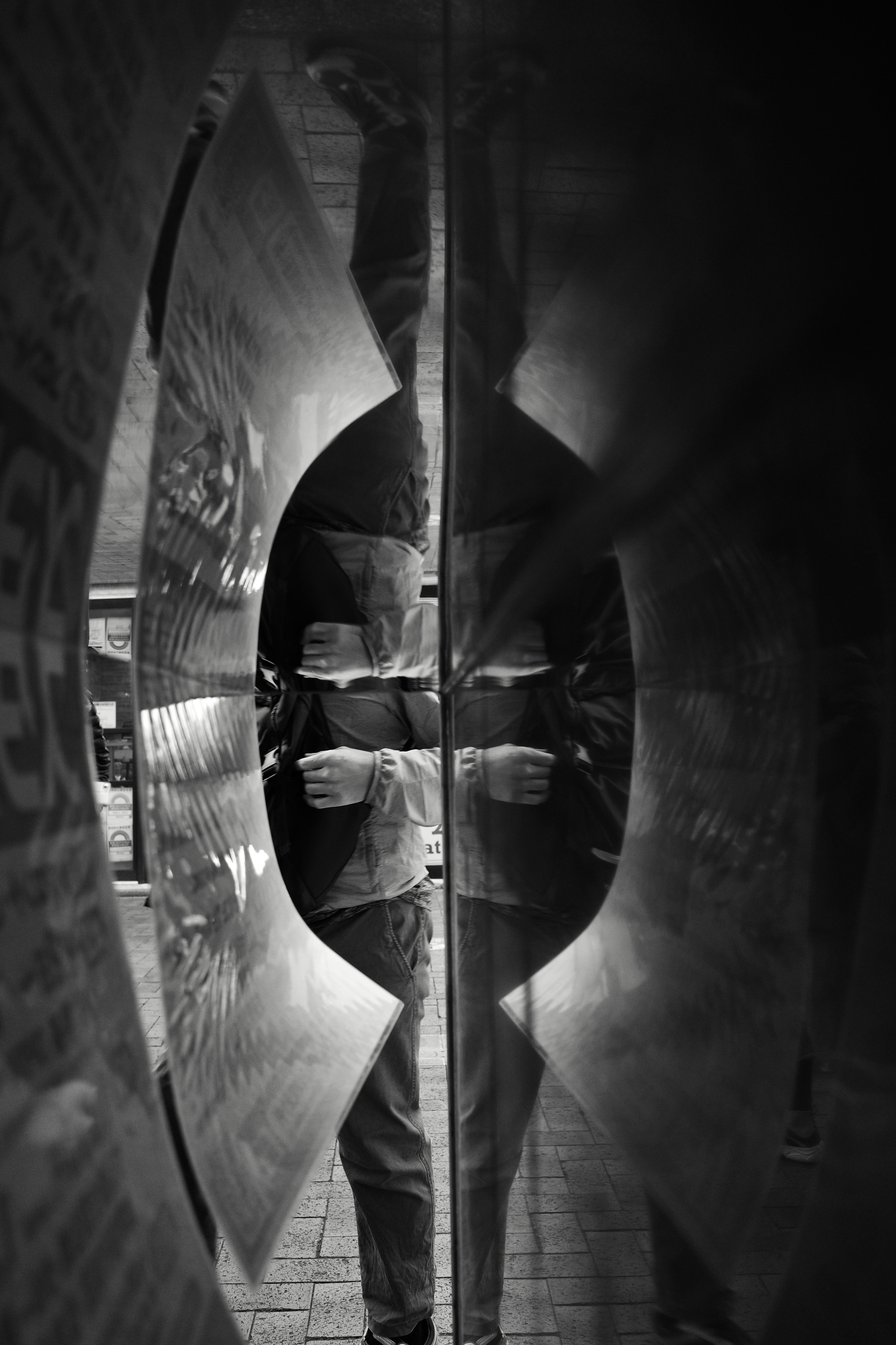 Monochrome image featuring a reflected figure in a distorted surface