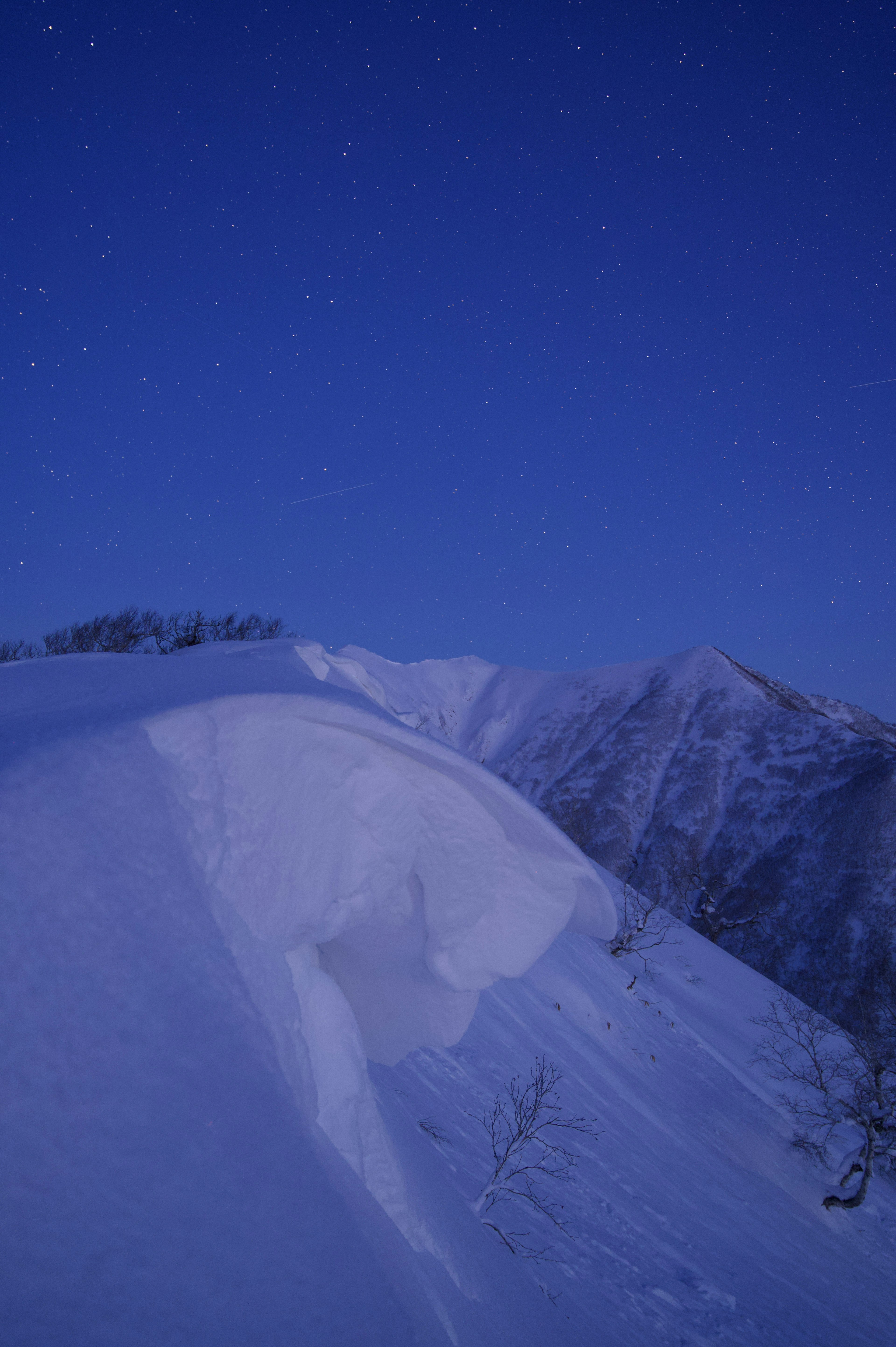 雪に覆われた山の稜線と星空の風景