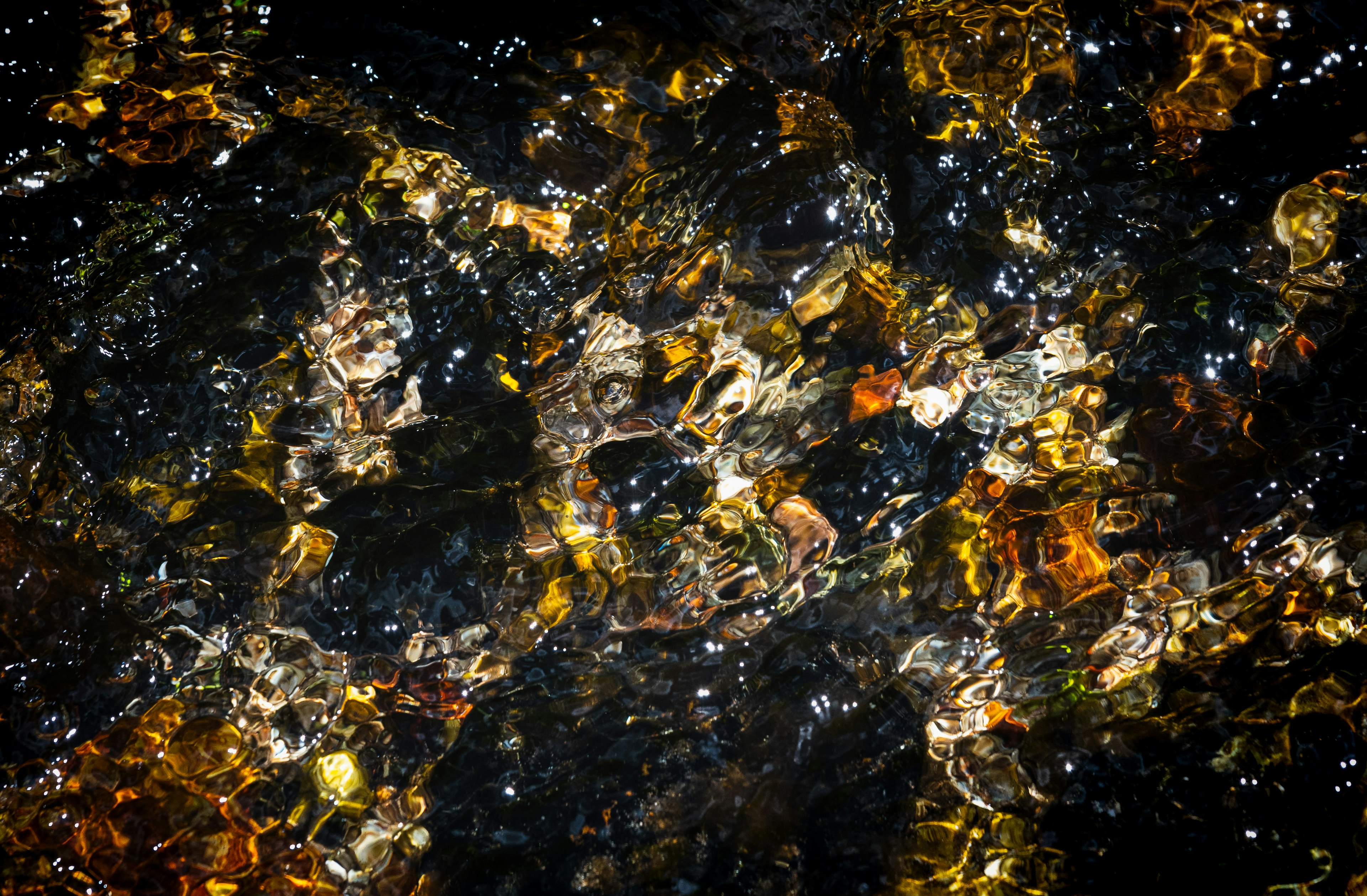 Wellenbewegte Wasseroberfläche mit dunklen und goldenen Farbtönen