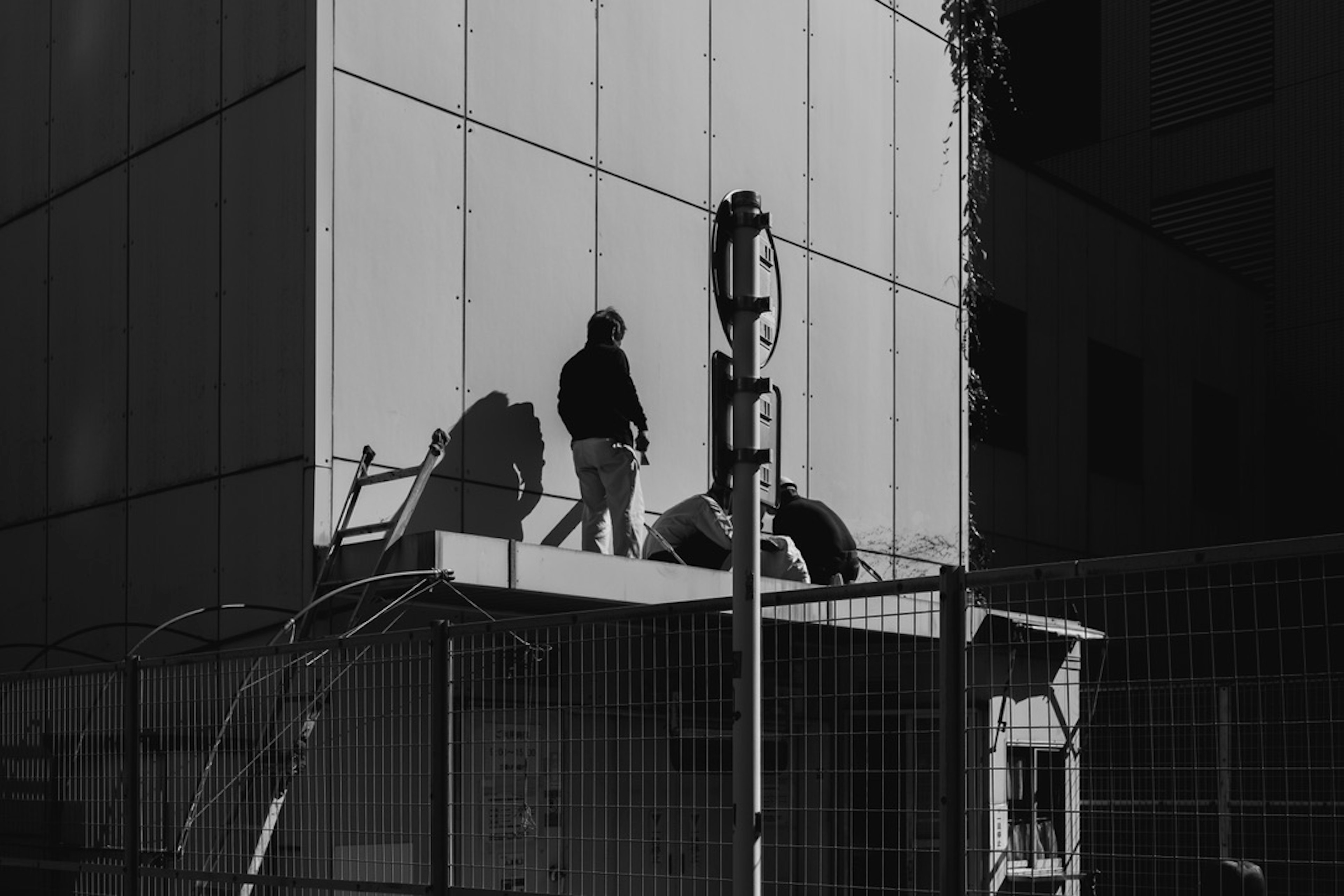 Silhouettes of workers on a building facade with glass reflections