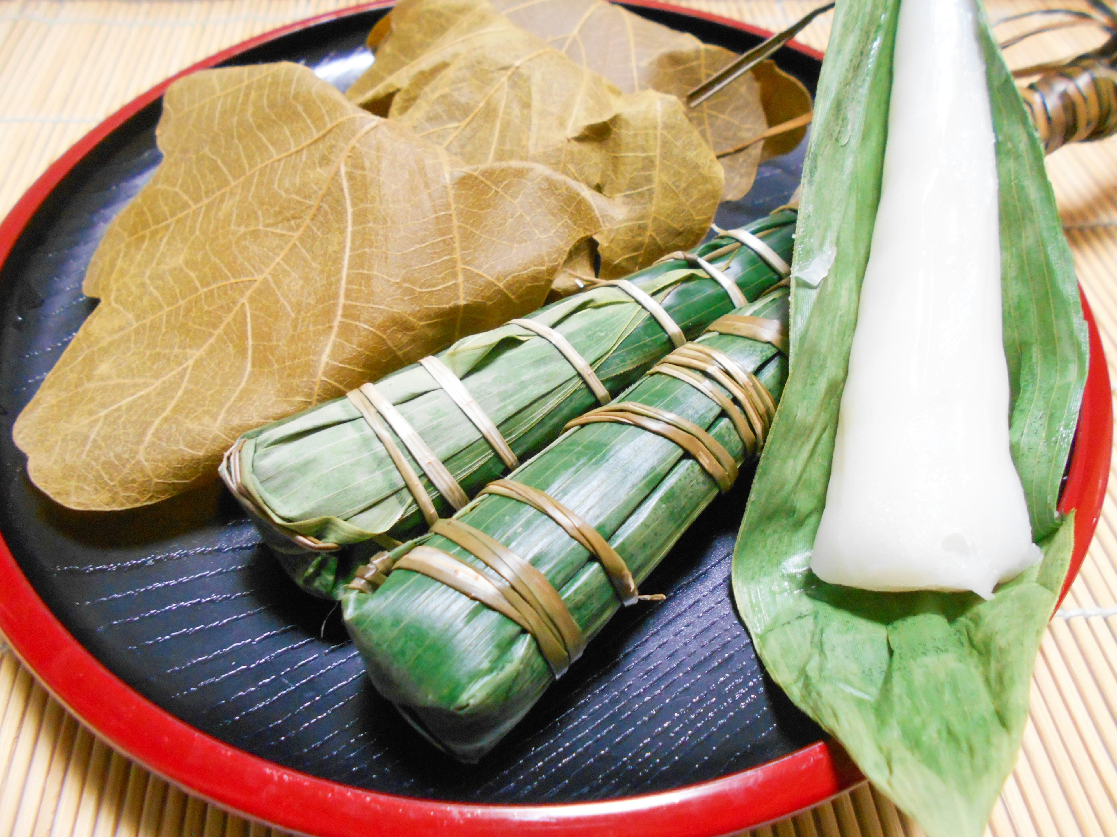 Green food items wrapped in leaves on a black plate