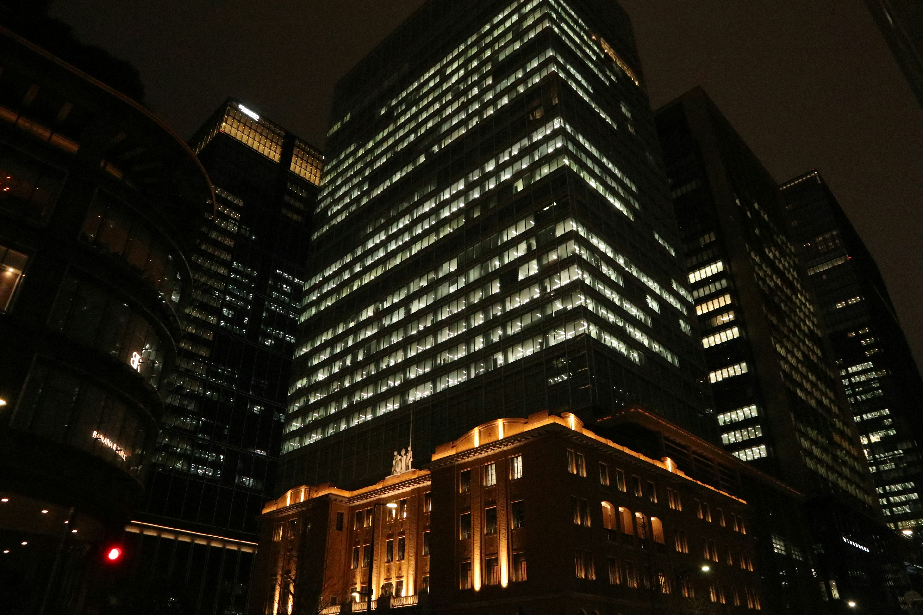 Modern skyscrapers illuminated at night with a historic building in the foreground