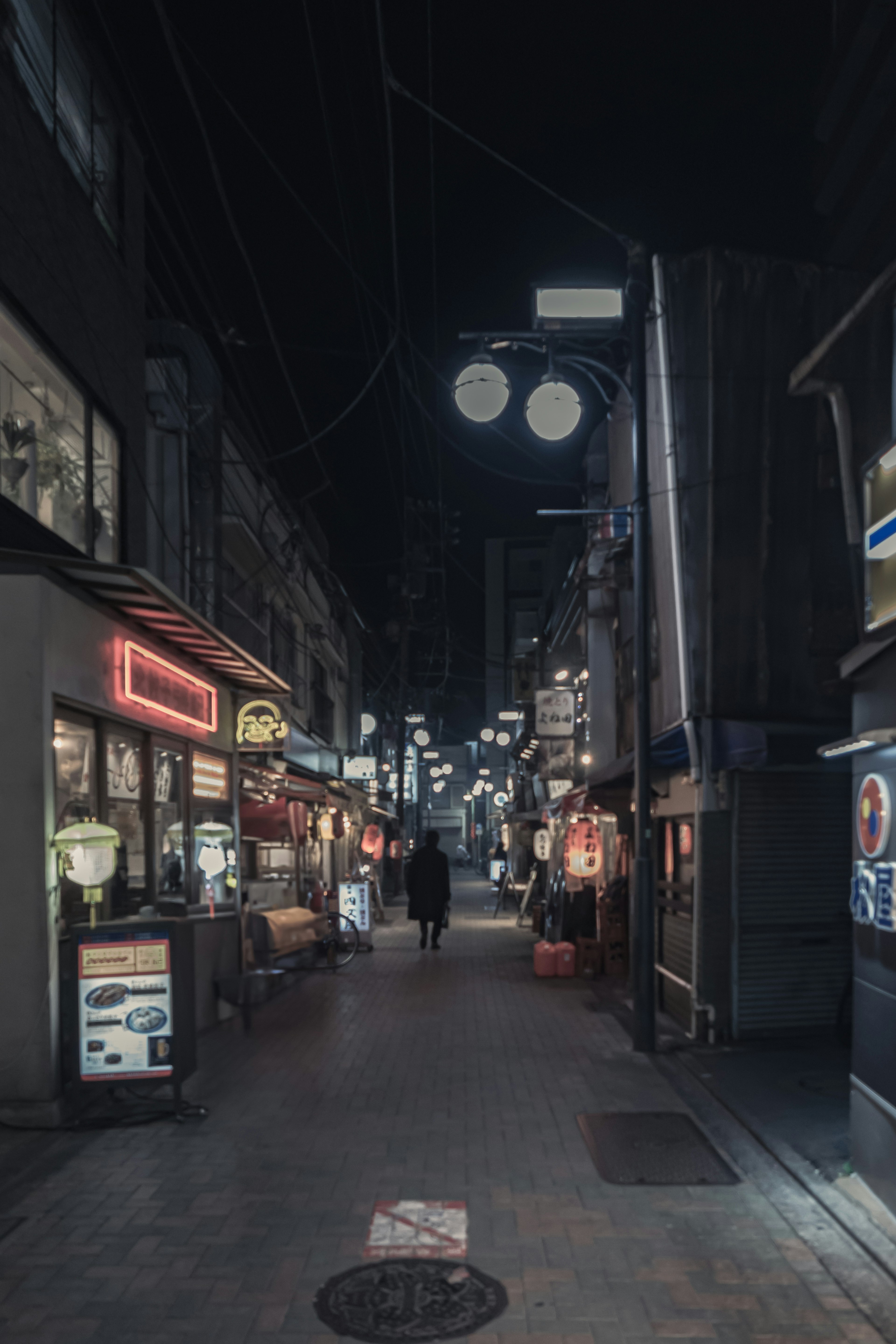 Calle estrecha de noche flanqueada por restaurantes iluminados