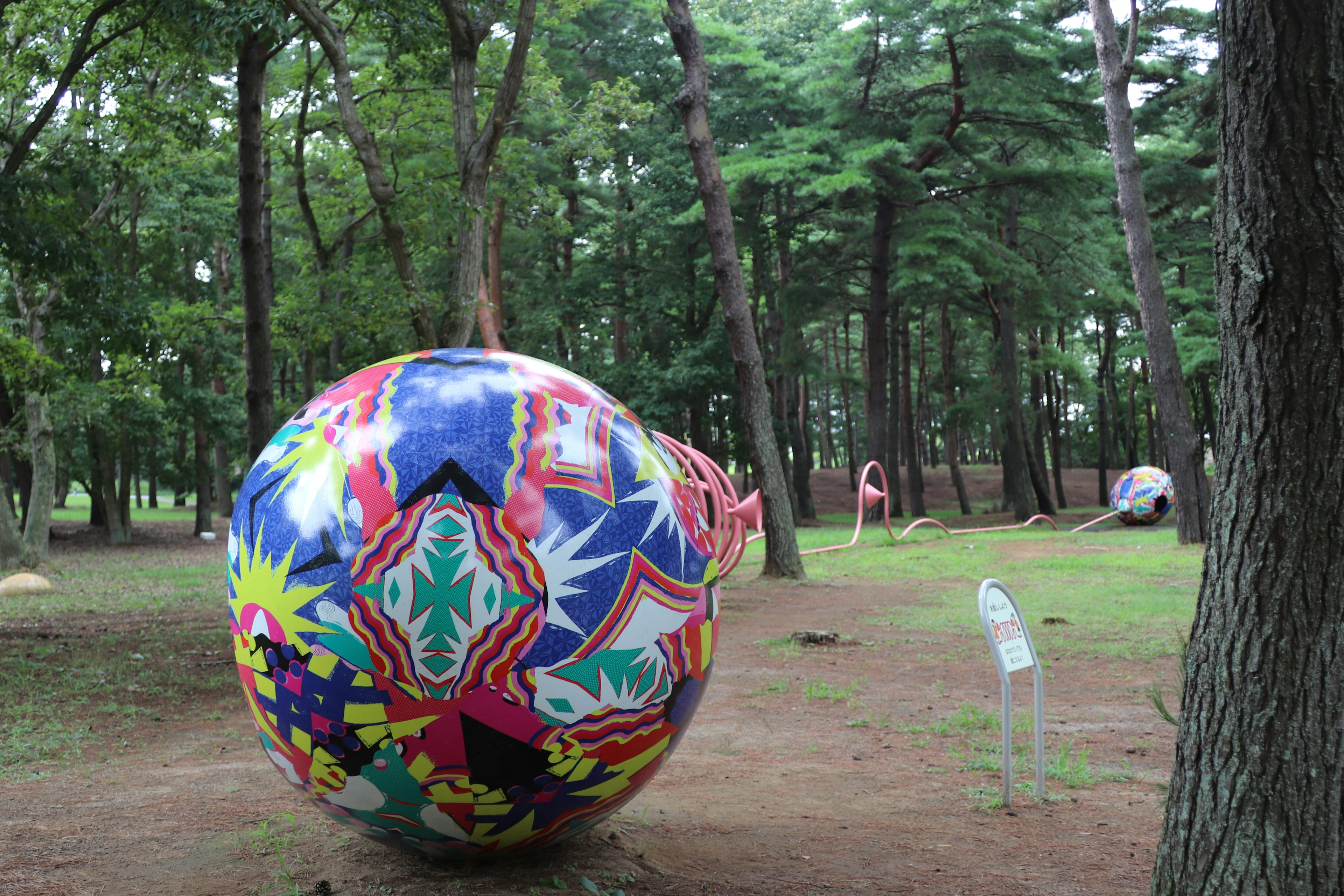 Grande sfera colorata con motivi posizionata in una foresta