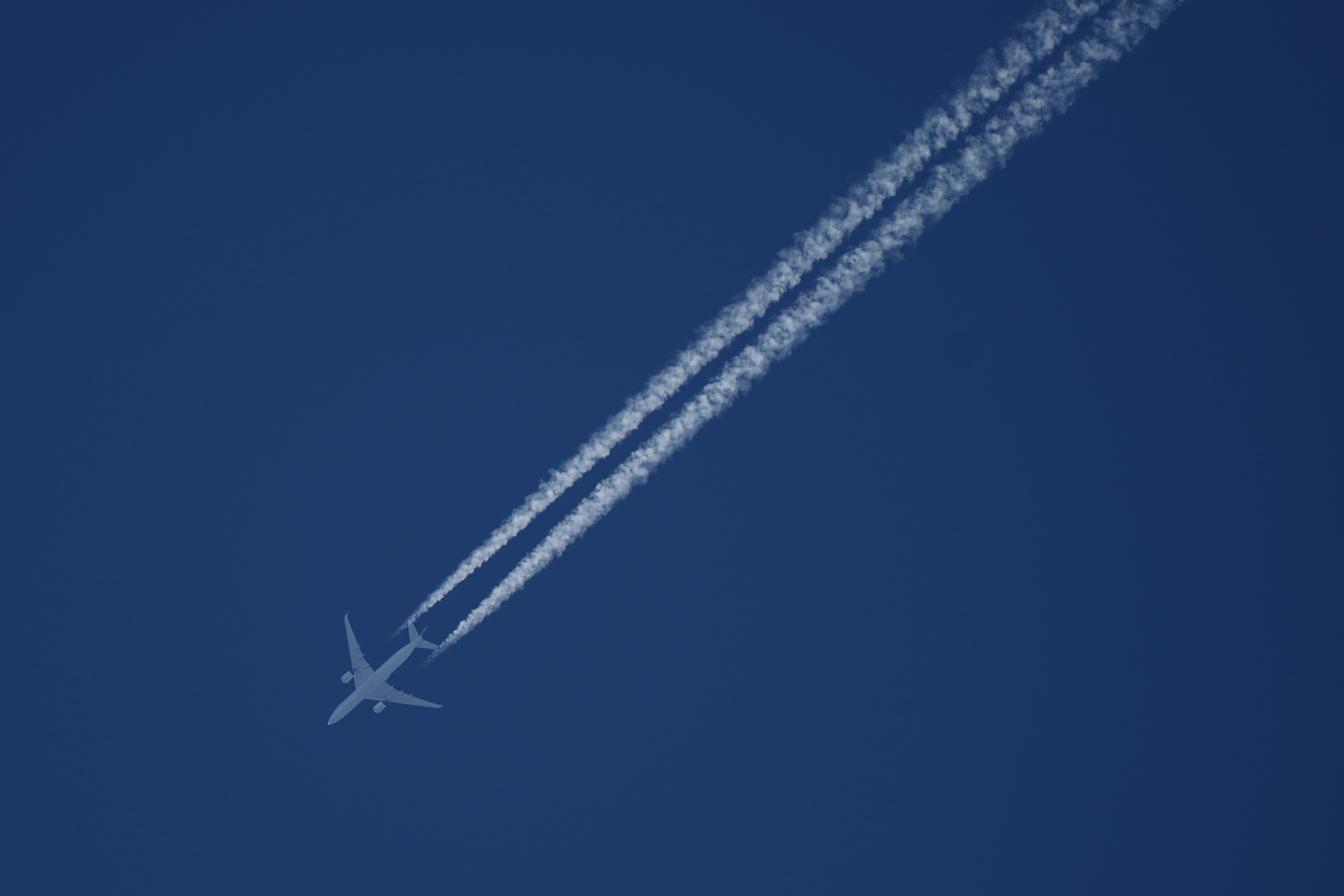 Avión volando en un cielo azul dejando estelas blancas