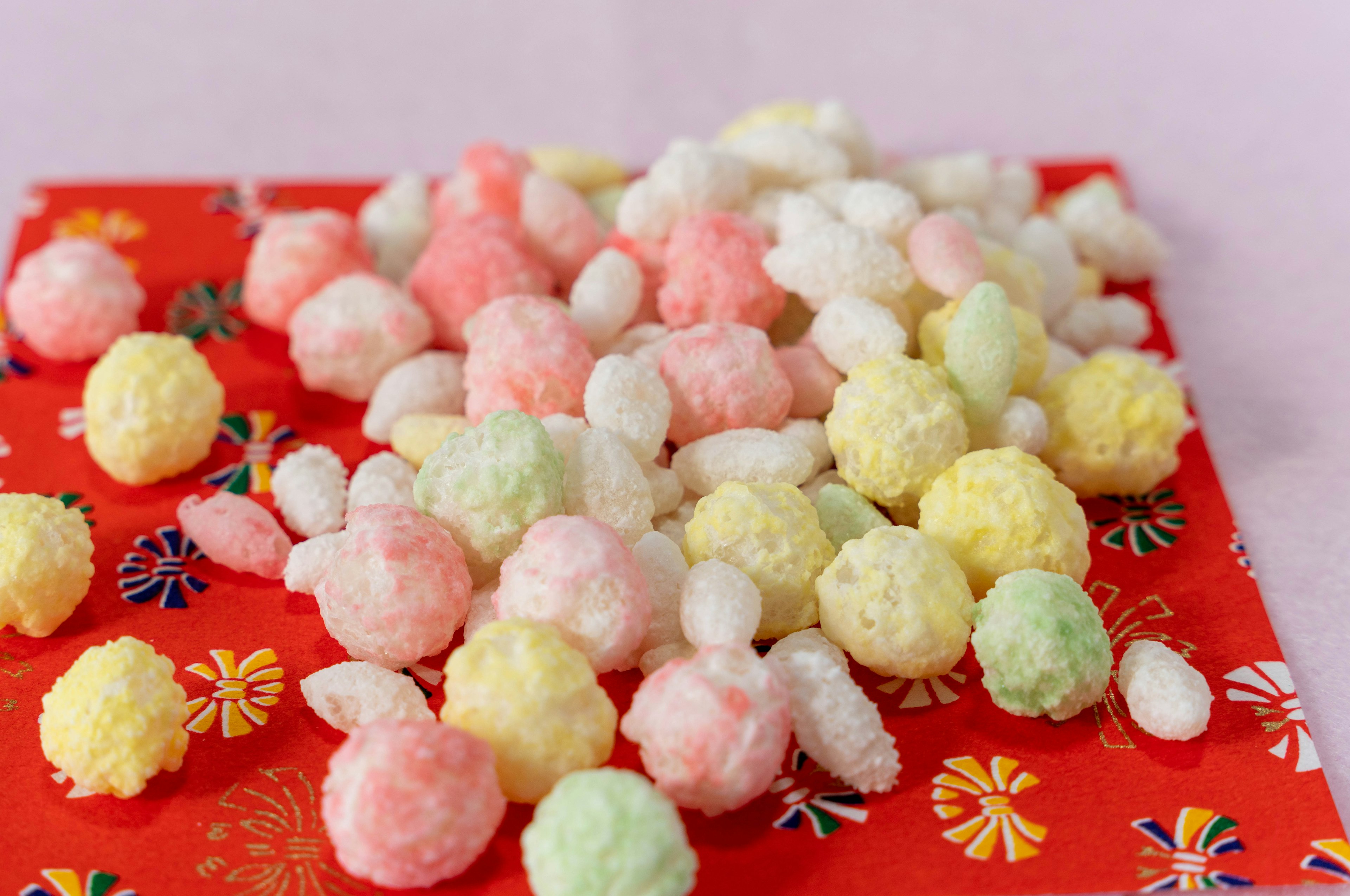 Petites boules de bonbons colorés éparpillées sur un tissu rouge