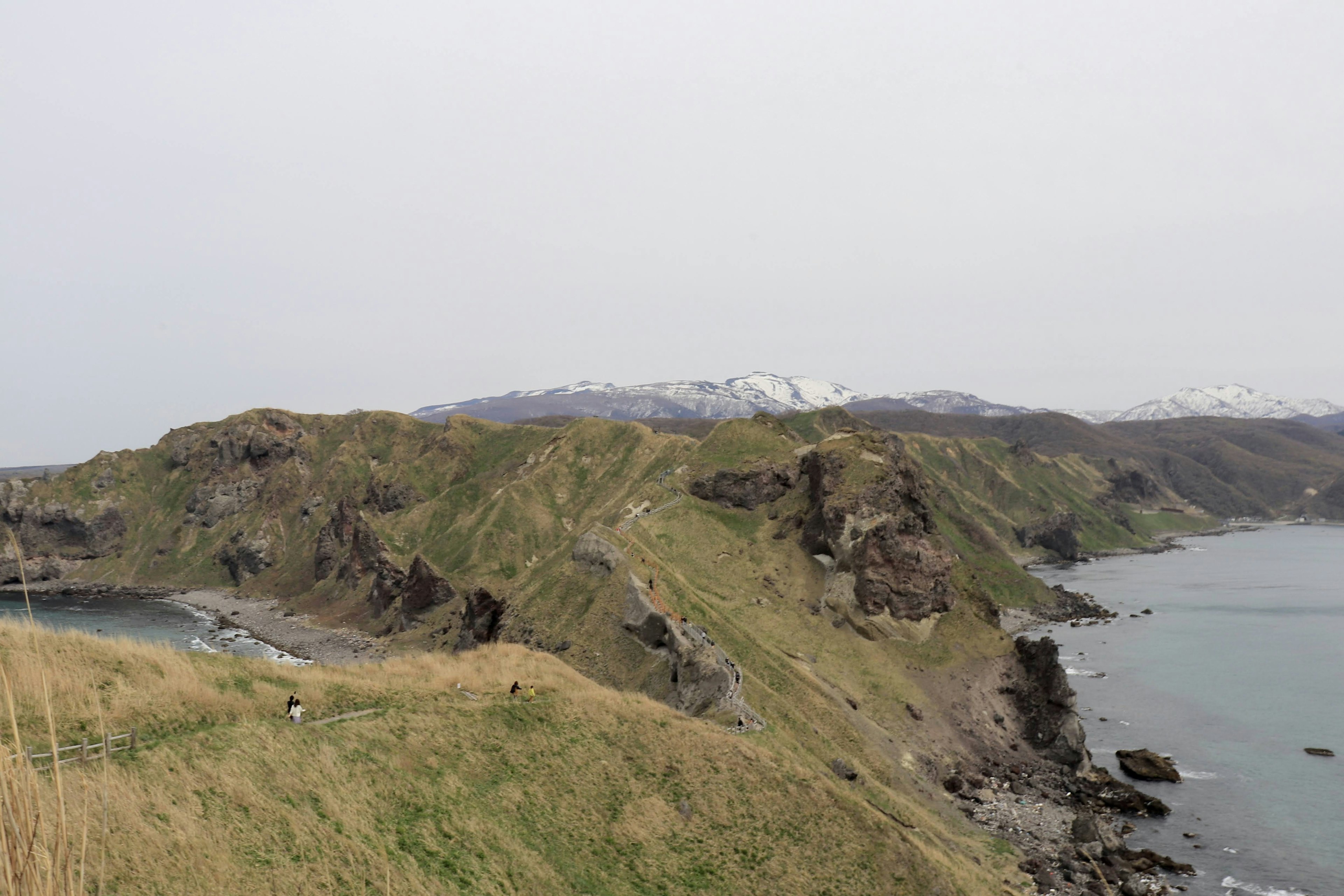 Coastal landscape featuring green hills and rocky shoreline