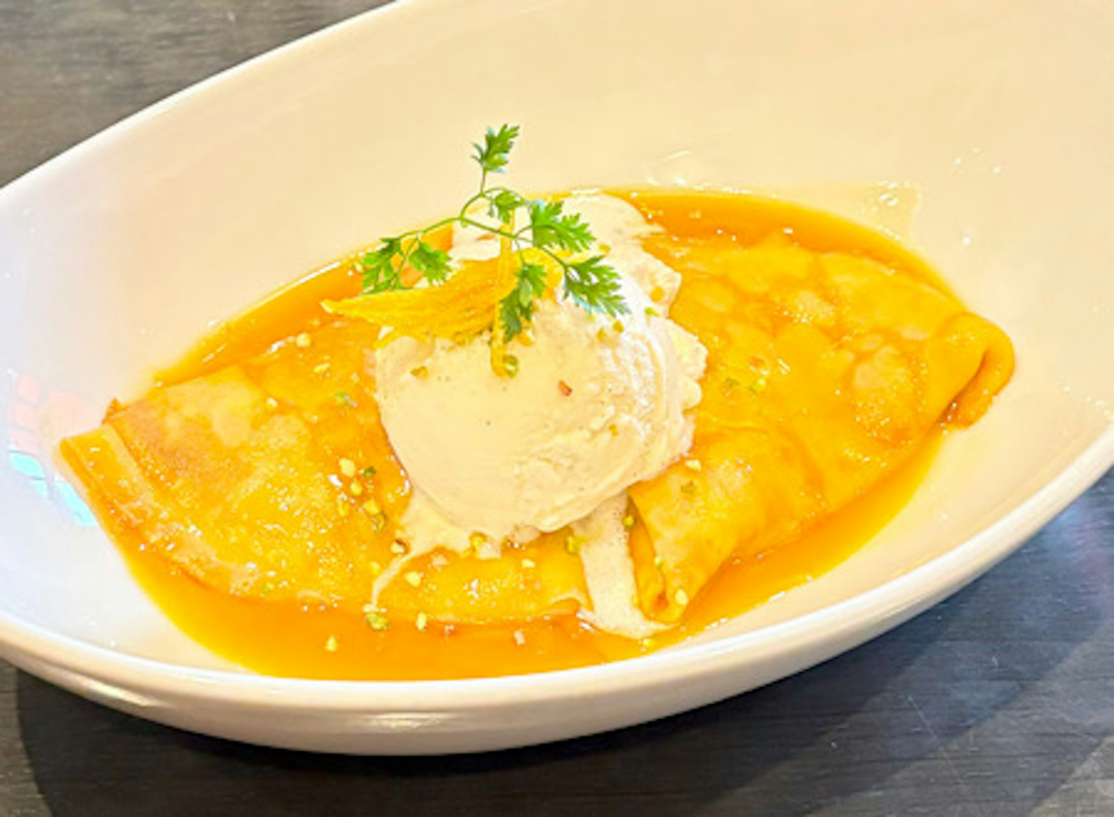 Crepe with orange sauce topped with ice cream and mint leaves