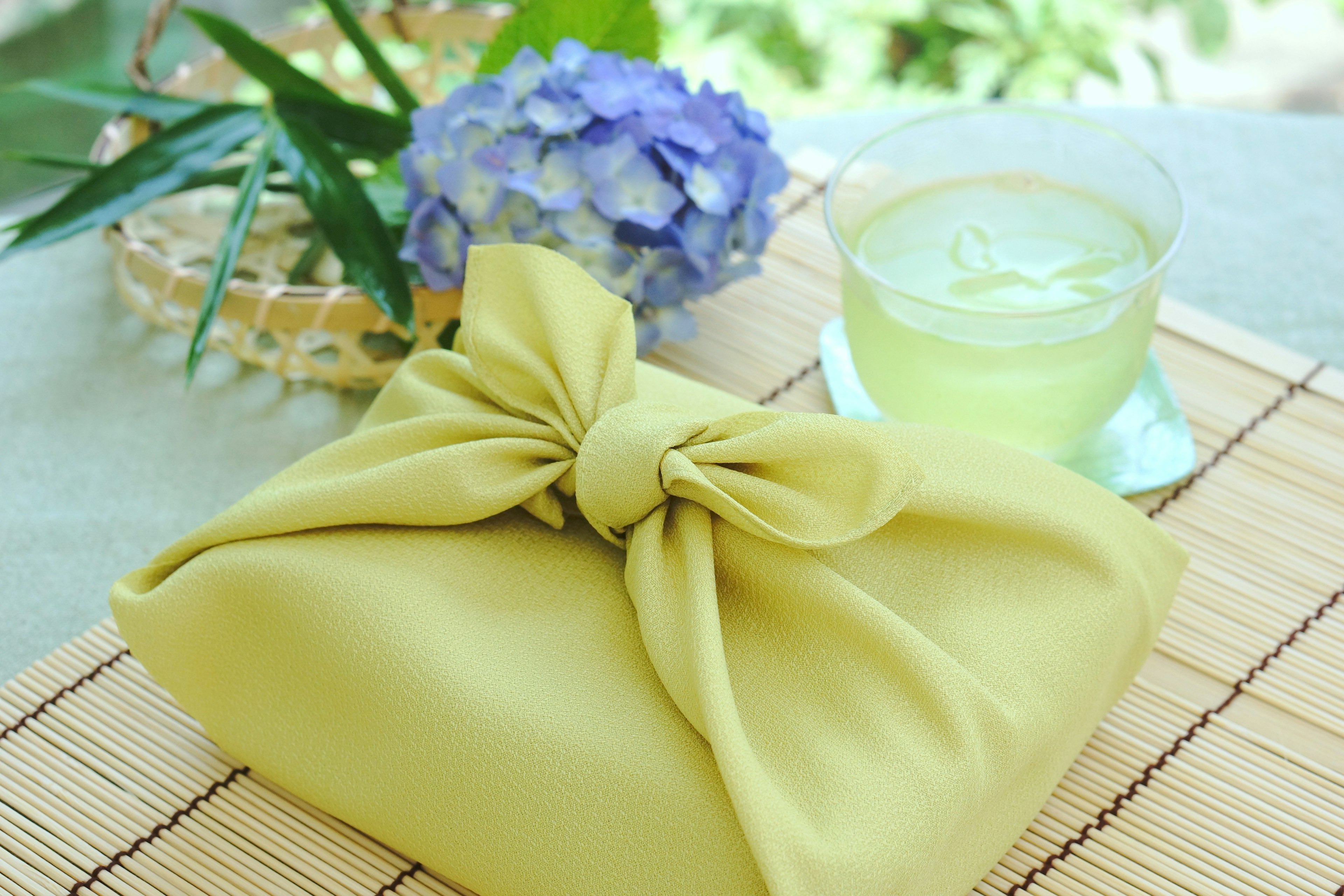 Yellow wrapped item with a bow, blue hydrangea flower, and a cold drink