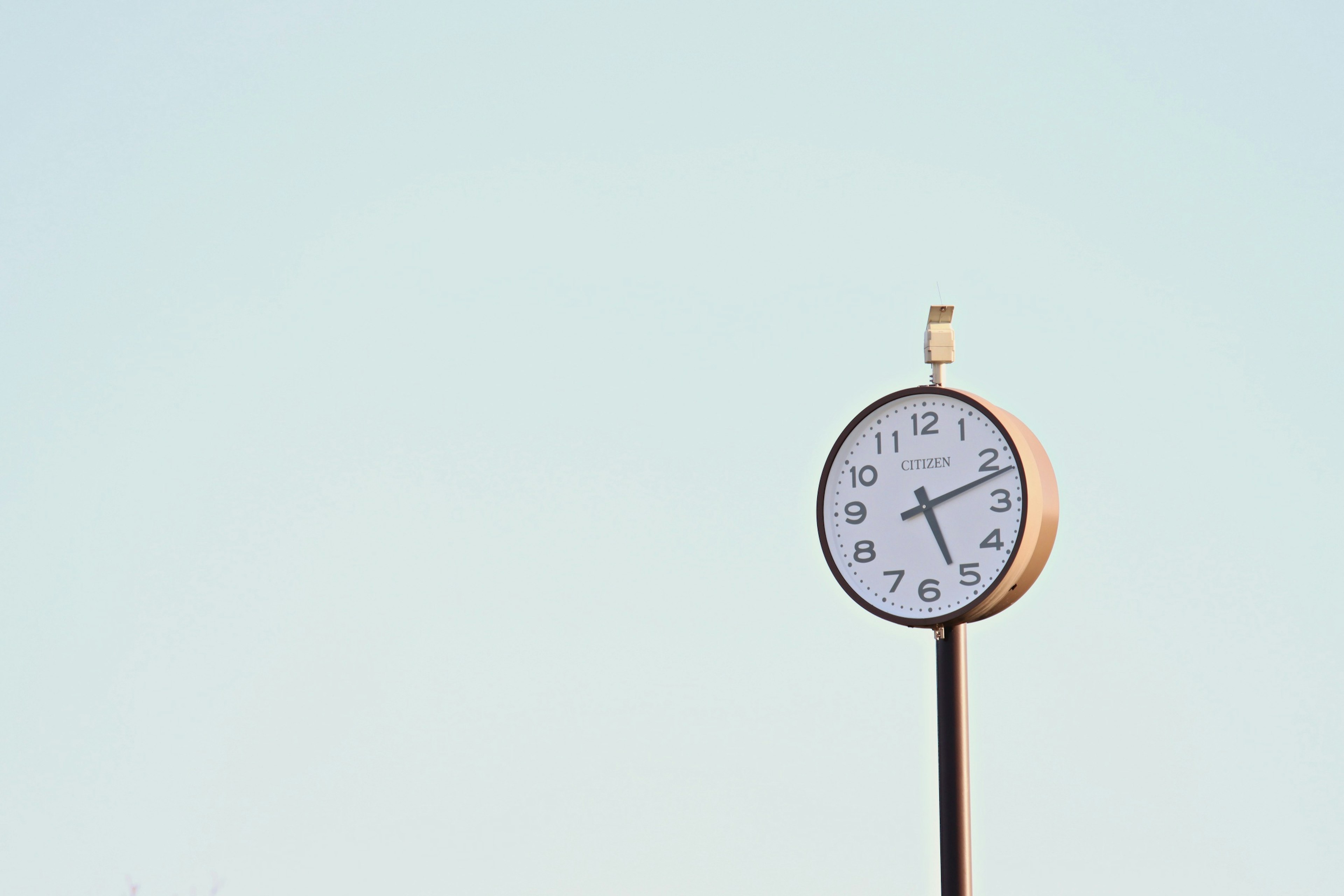 Analog clock standing under a clear blue sky