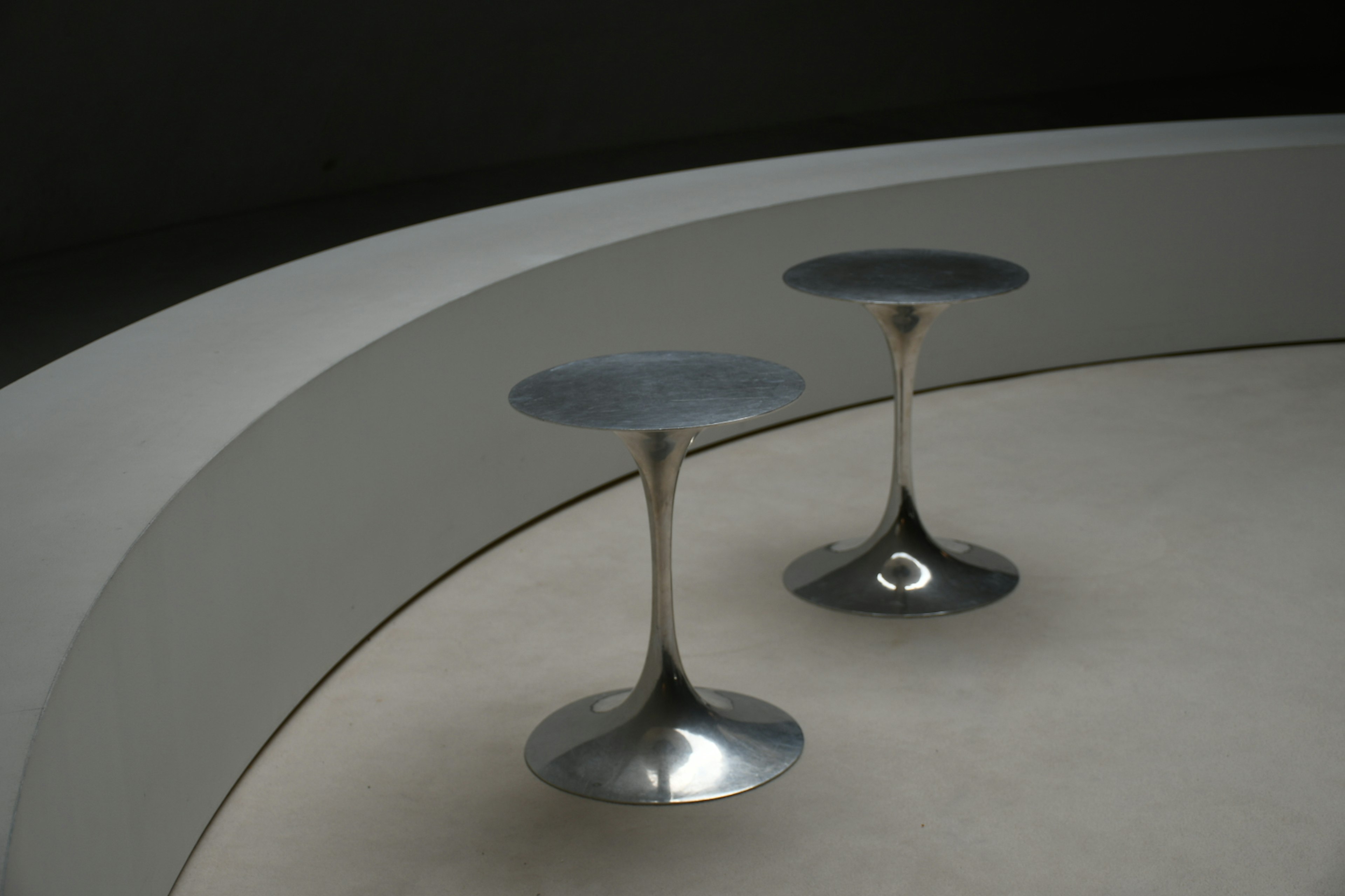 Modern interior corner featuring two silver pedestal tables with circular tops