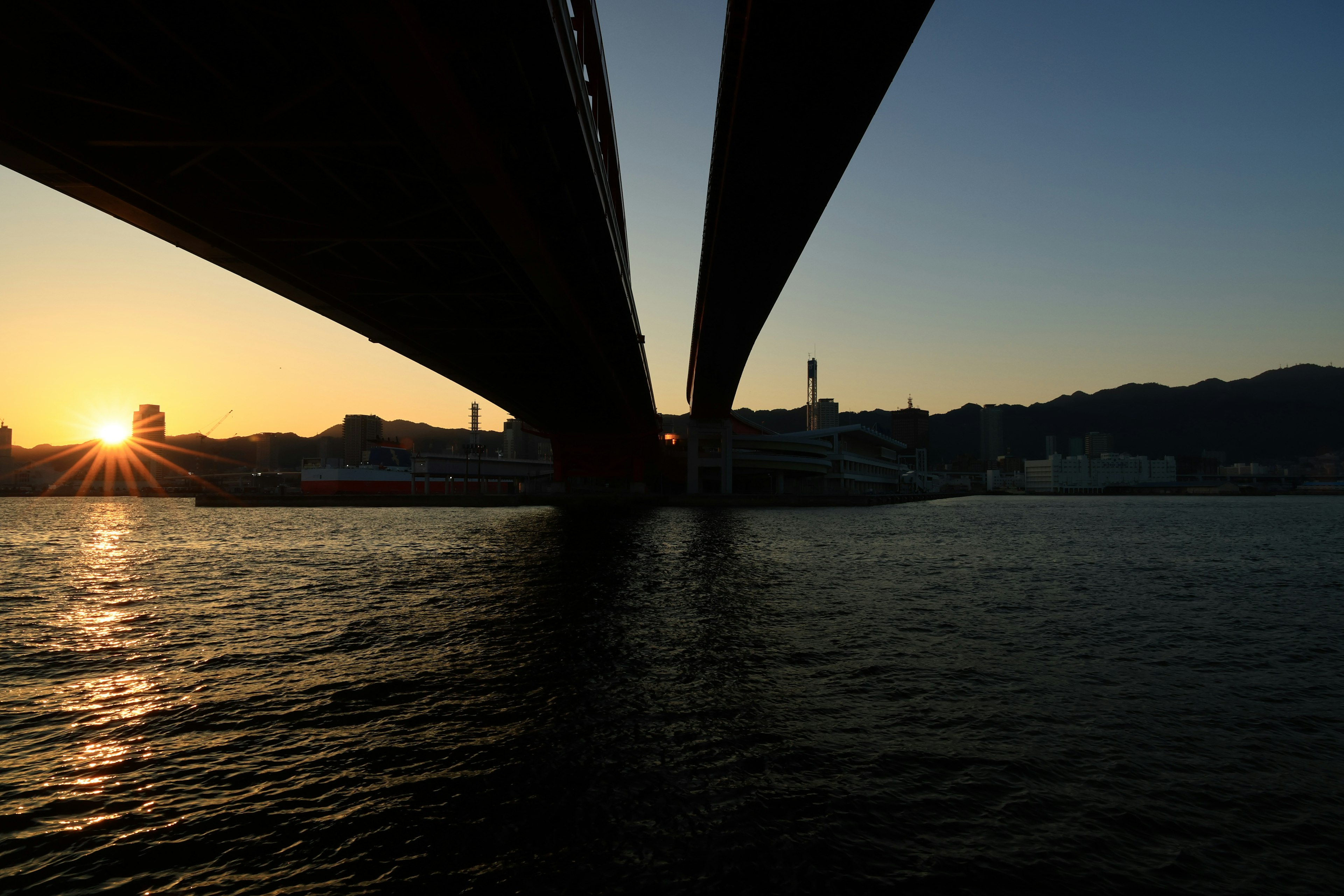 Sunset viewed from under a bridge with reflections on the water