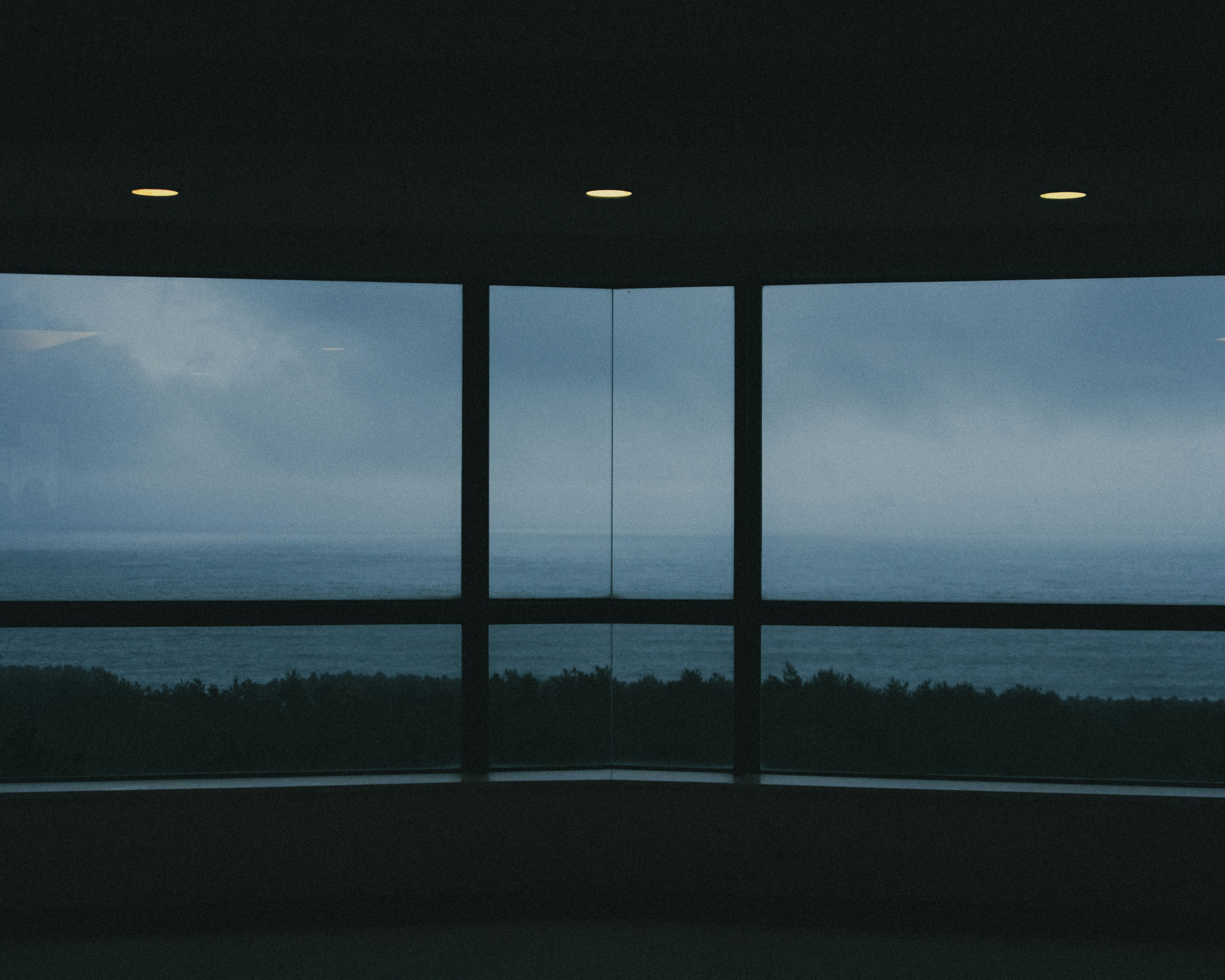 View of the blue sea and cloudy sky through a large window