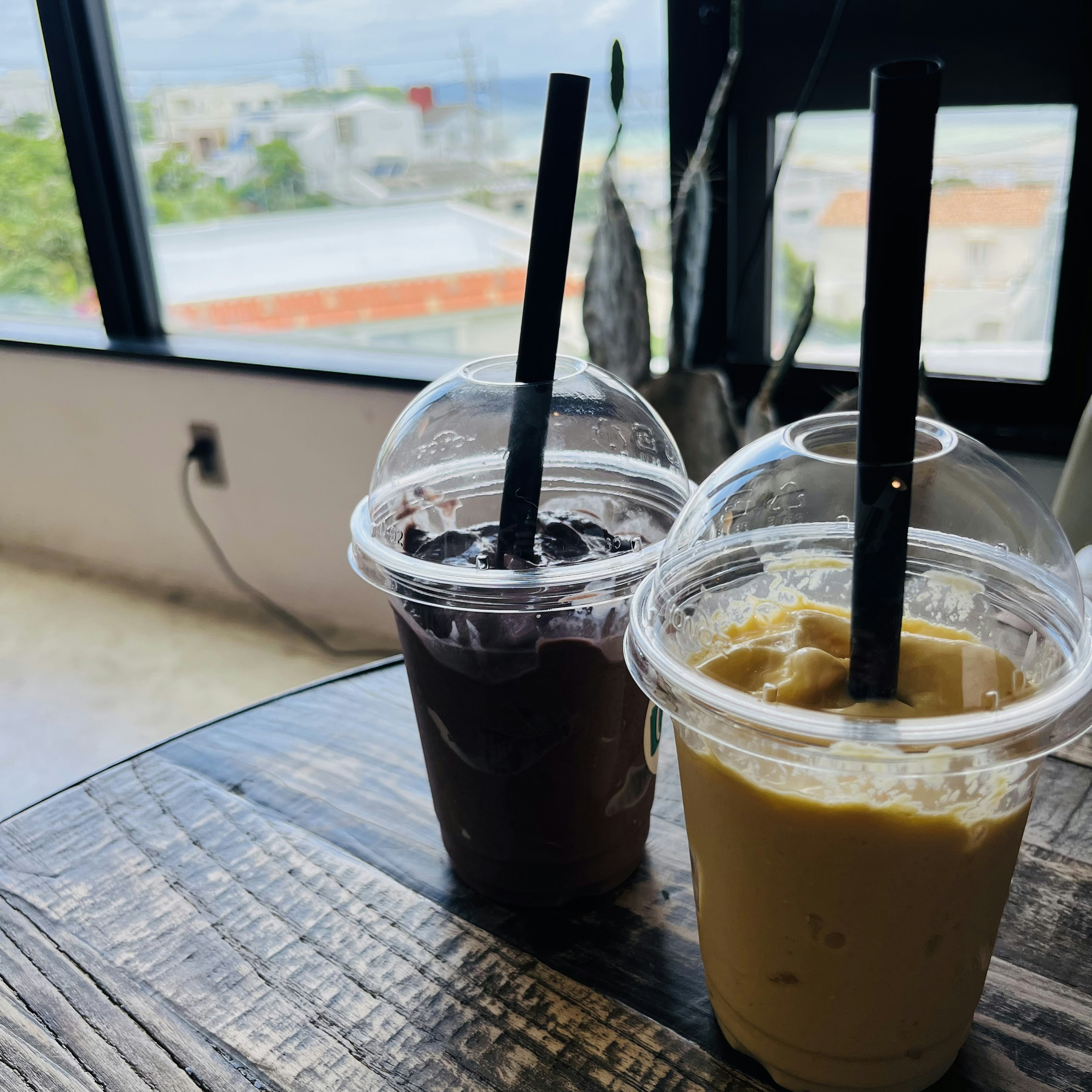 Dos bebidas frías sobre una mesa de madera una oscura y una cremosa