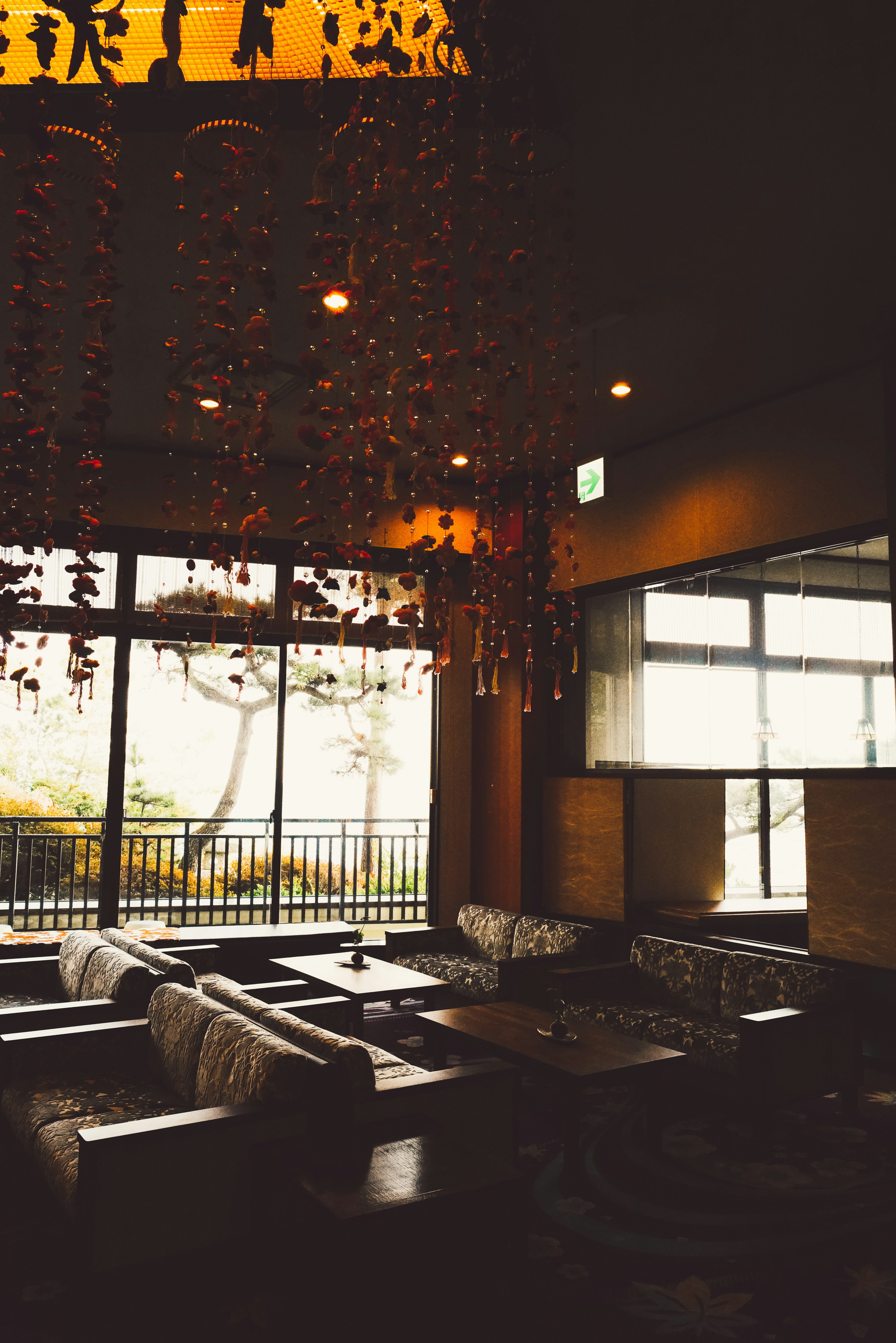 Interior de una cafetería acogedora con grandes ventanas y un candelabro decorativo