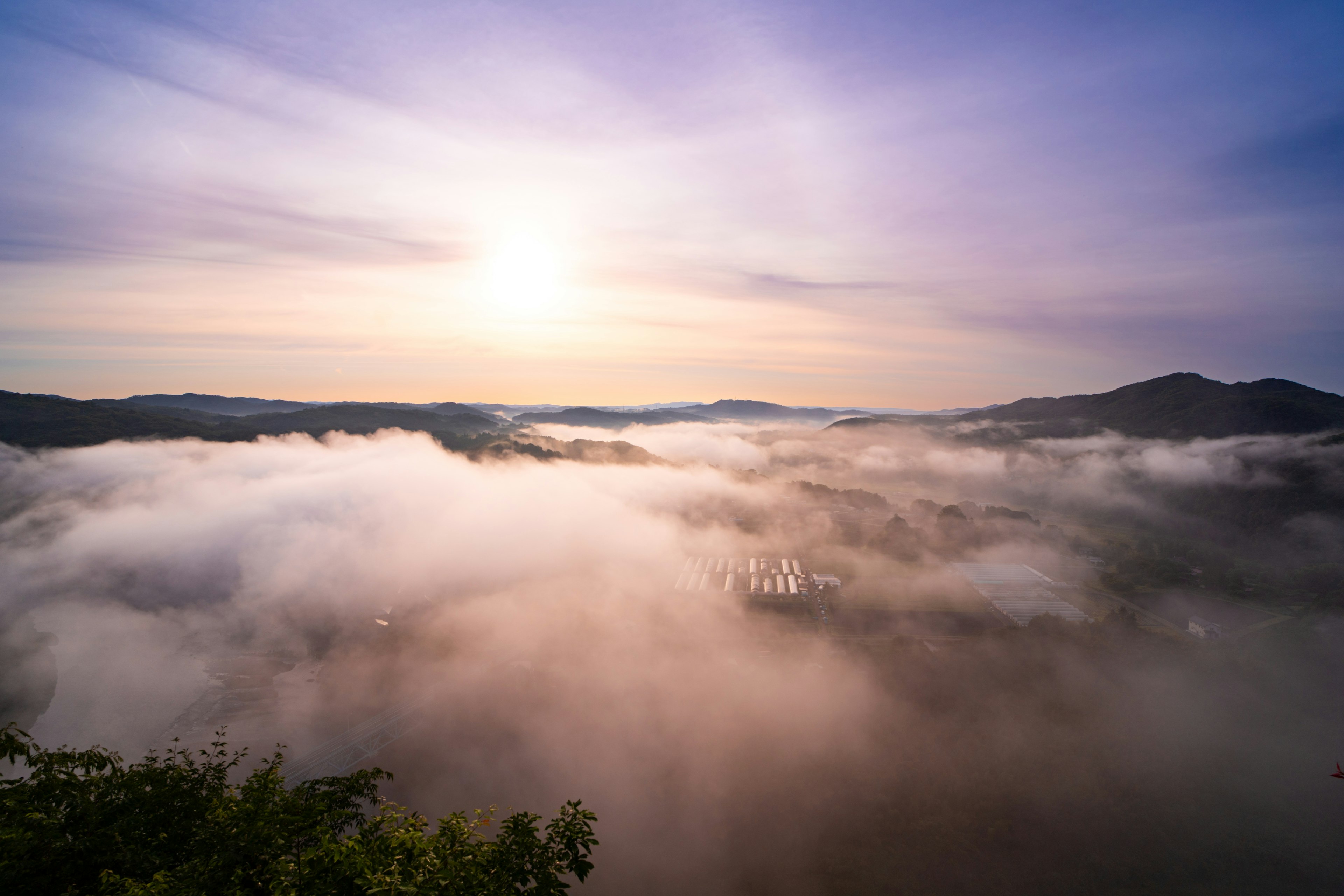 Vue magnifique des montagnes enveloppées de brouillard avec le soleil levant