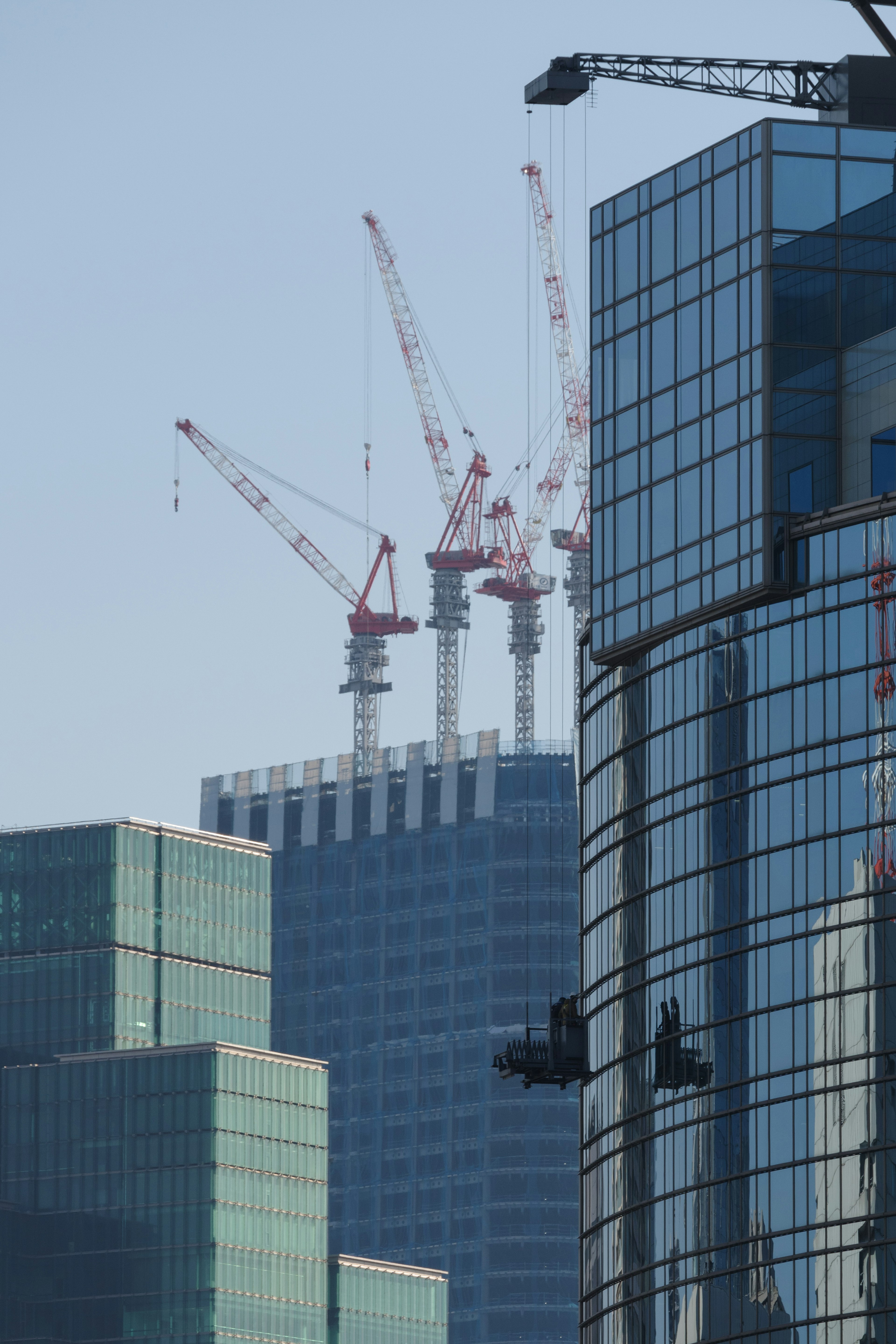 Urban skyline featuring construction cranes atop a skyscraper