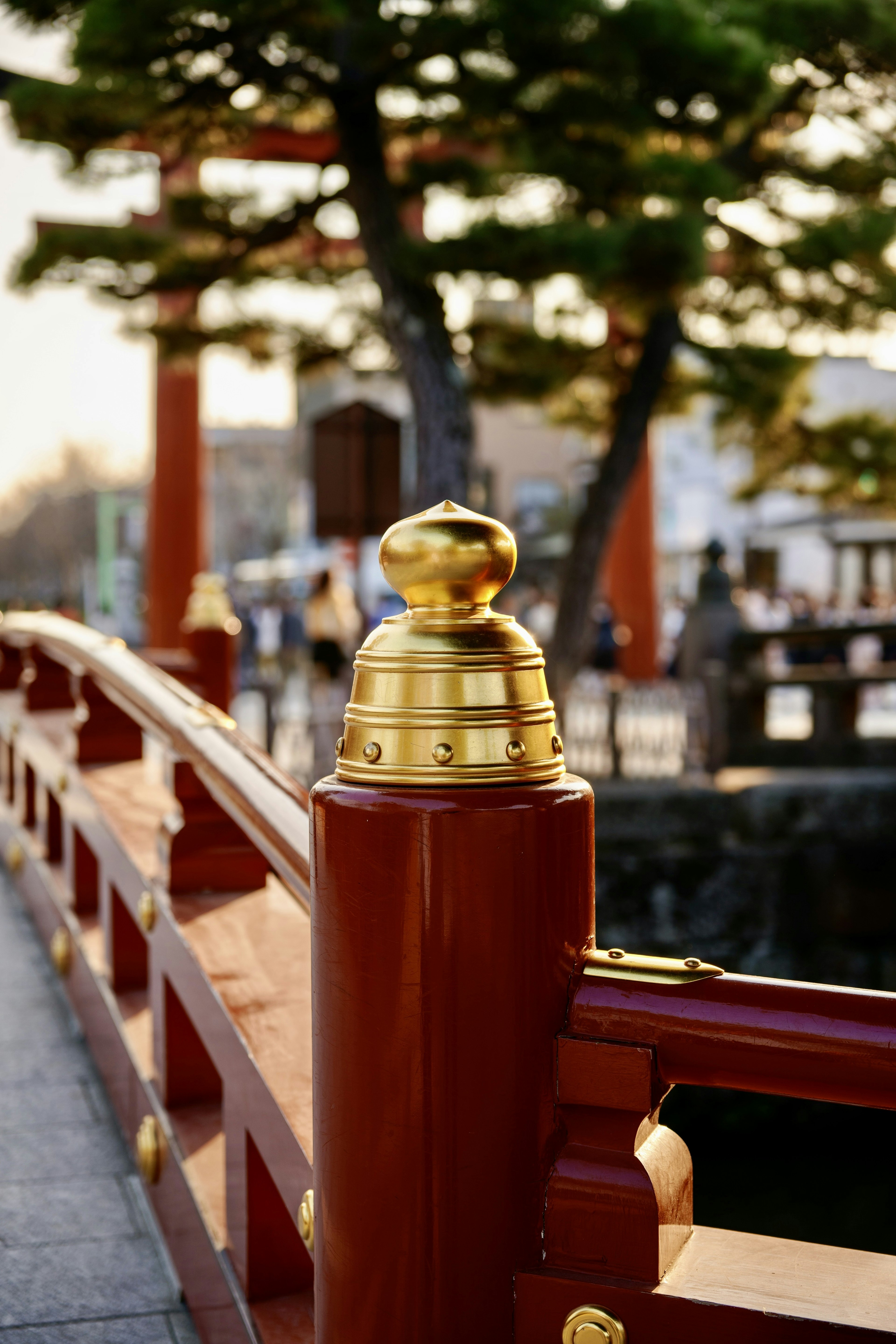 赤い橋の金色の柱頭と緑の木々が映える風景