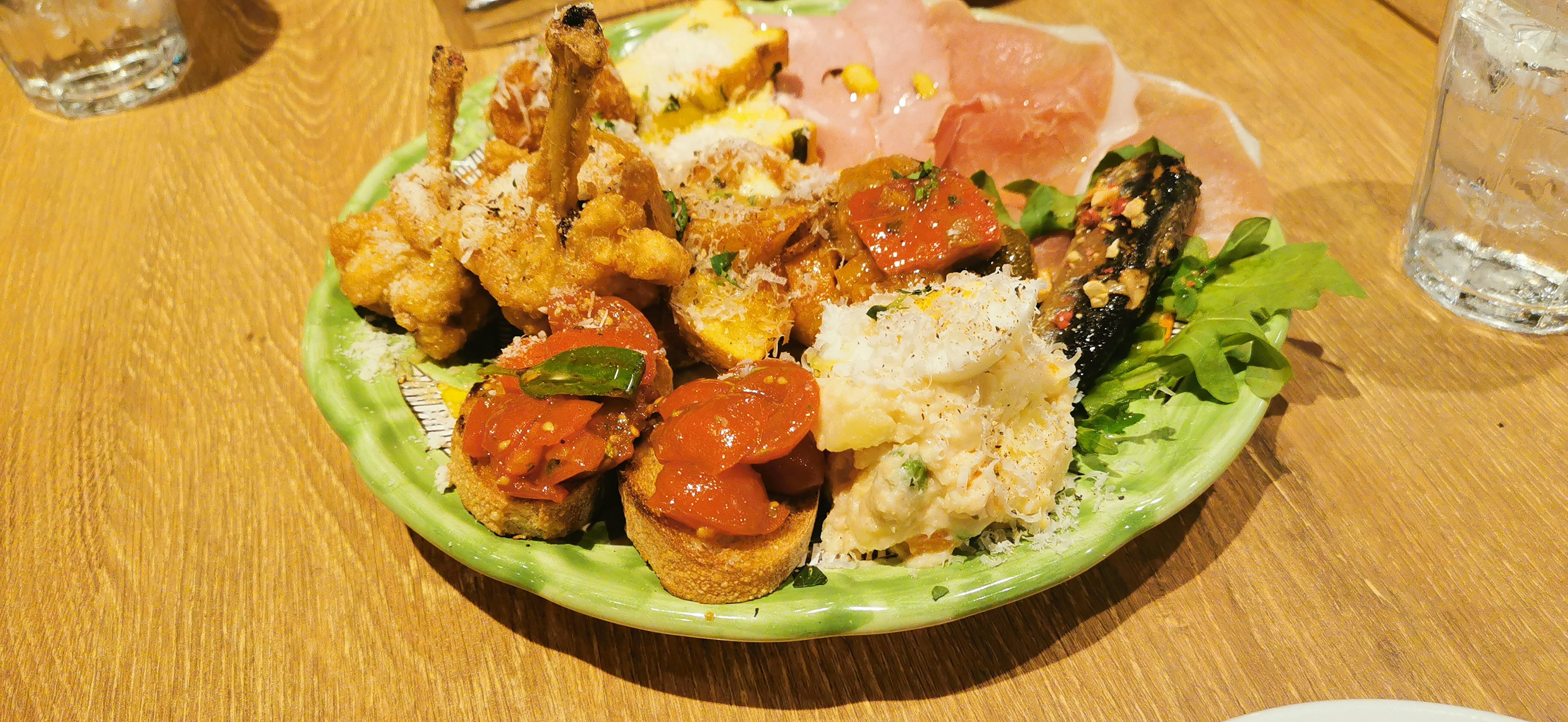 Platos coloridos dispuestos en un plato verde con varios alimentos