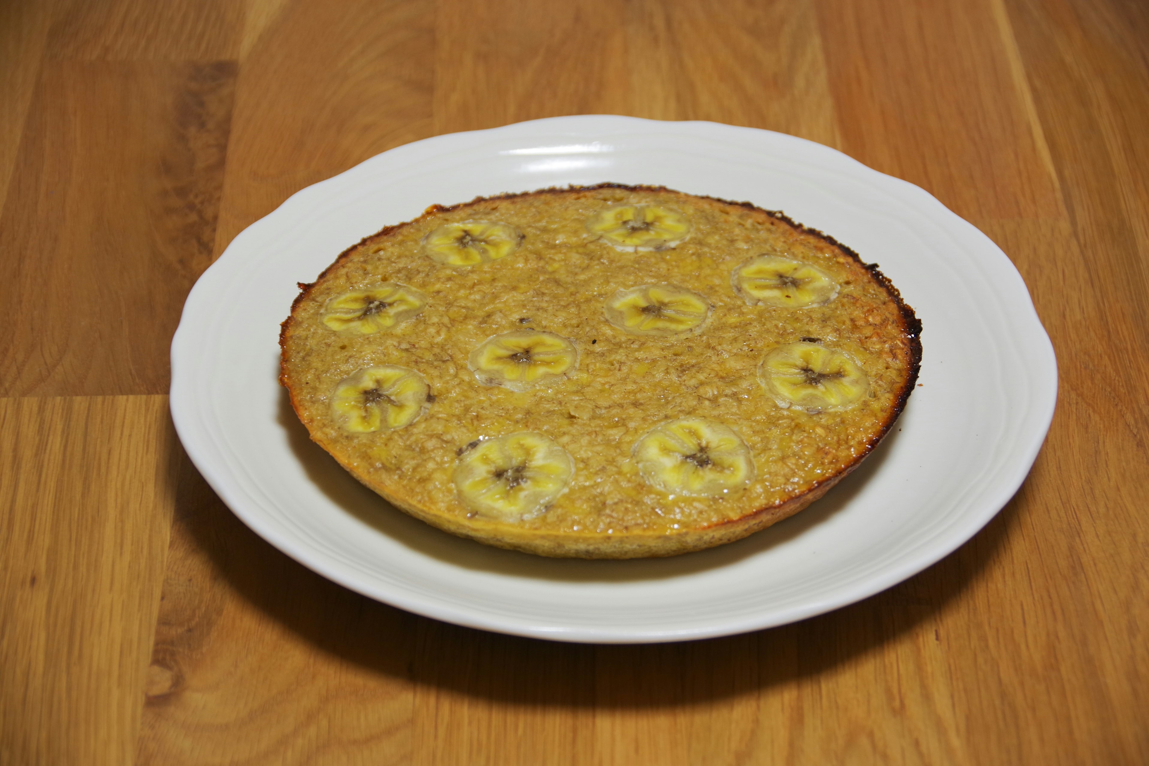 バナナのスライスがトッピングされた焼き菓子が白い皿に載っている