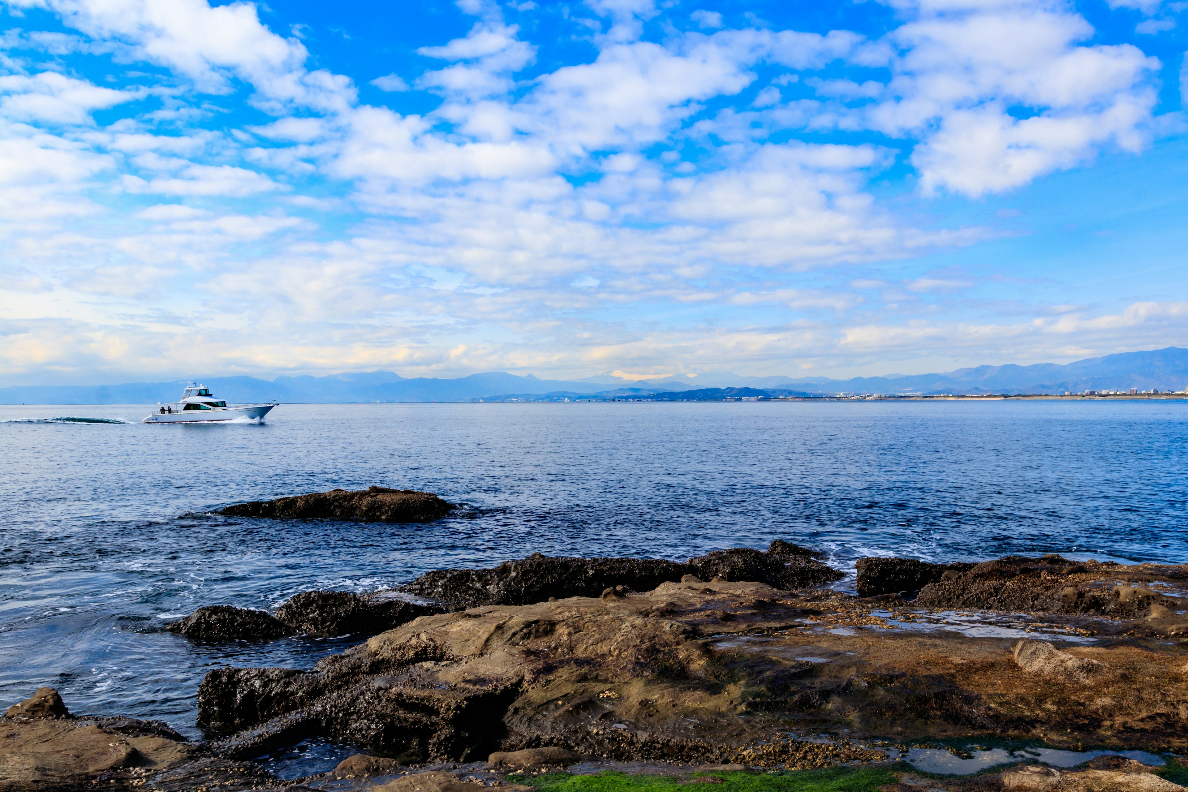 Barca che galleggia sulla costa sotto un cielo blu con nuvole