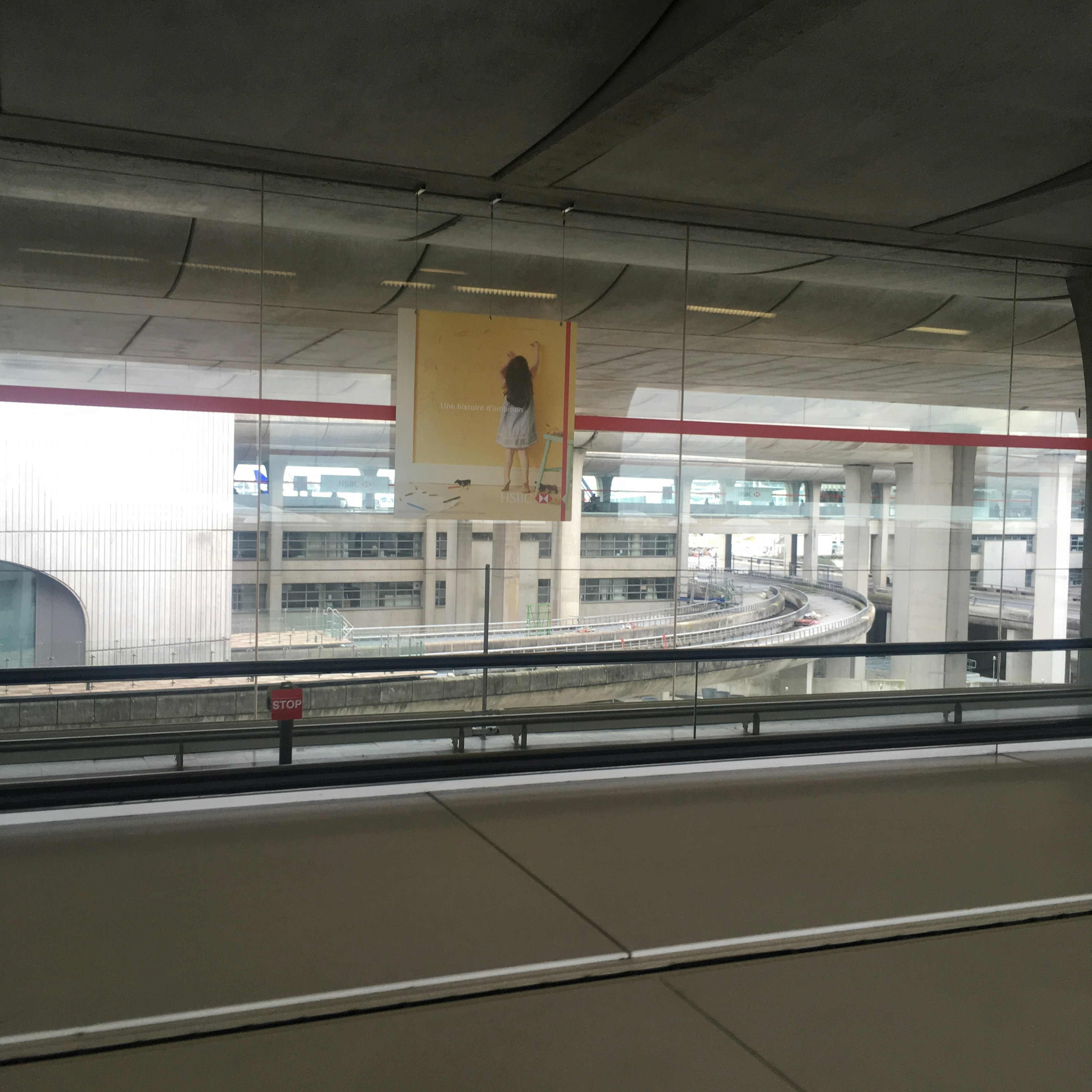 Vue d'une zone d'attente d'aéroport avec une affiche et des voies de train