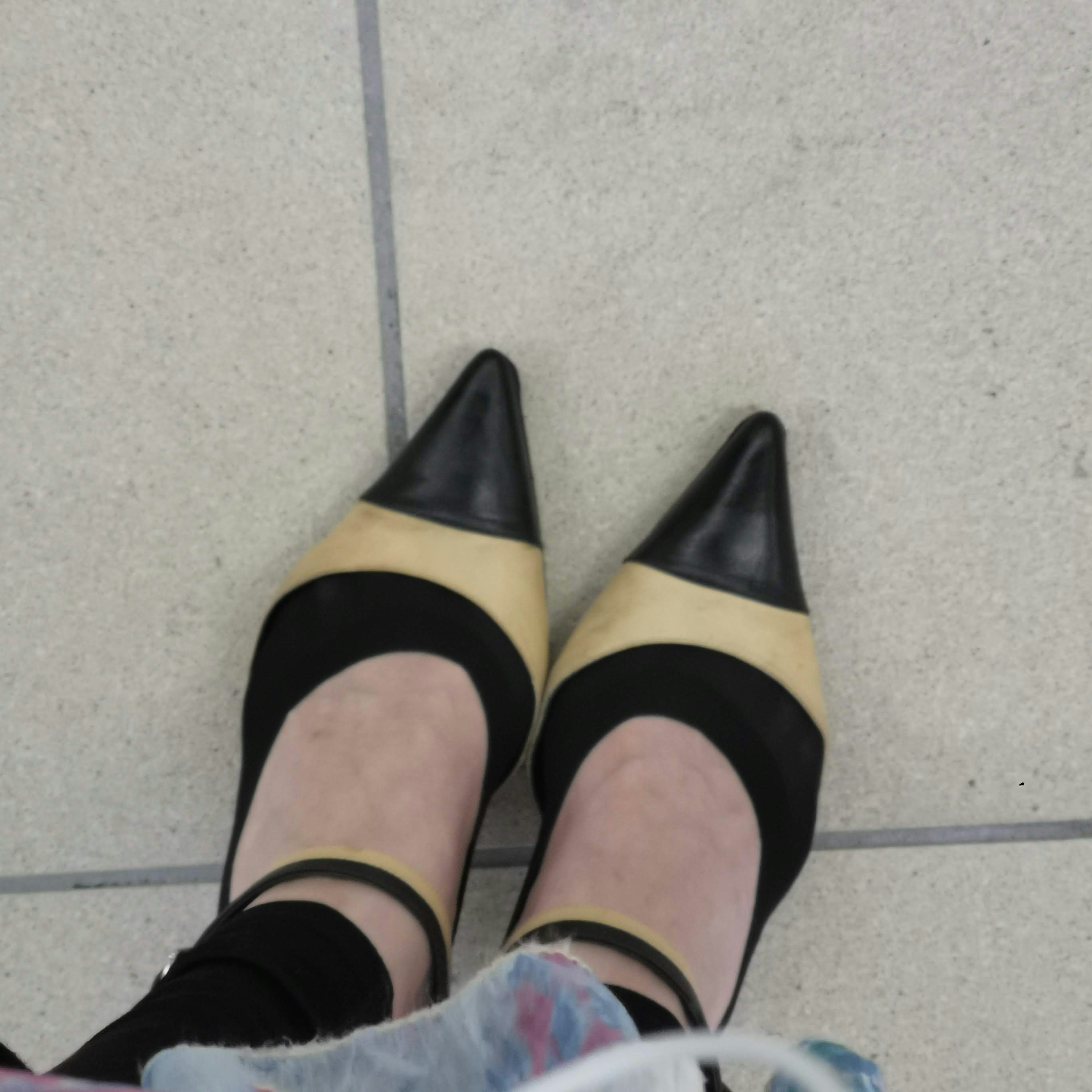 Close-up of black and beige high heels on a tiled floor