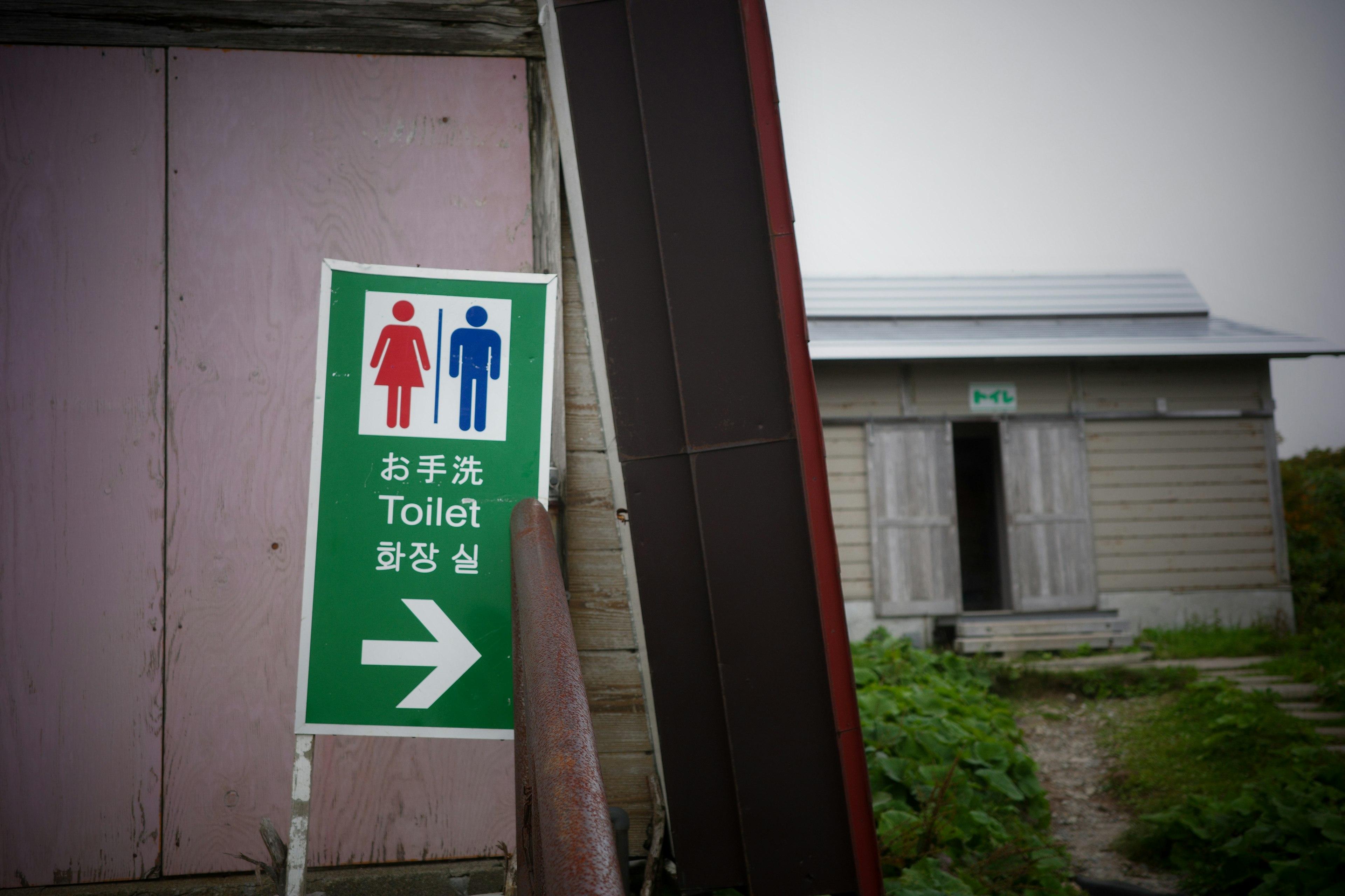 Toilet sign featuring male and female icons with an adjacent building