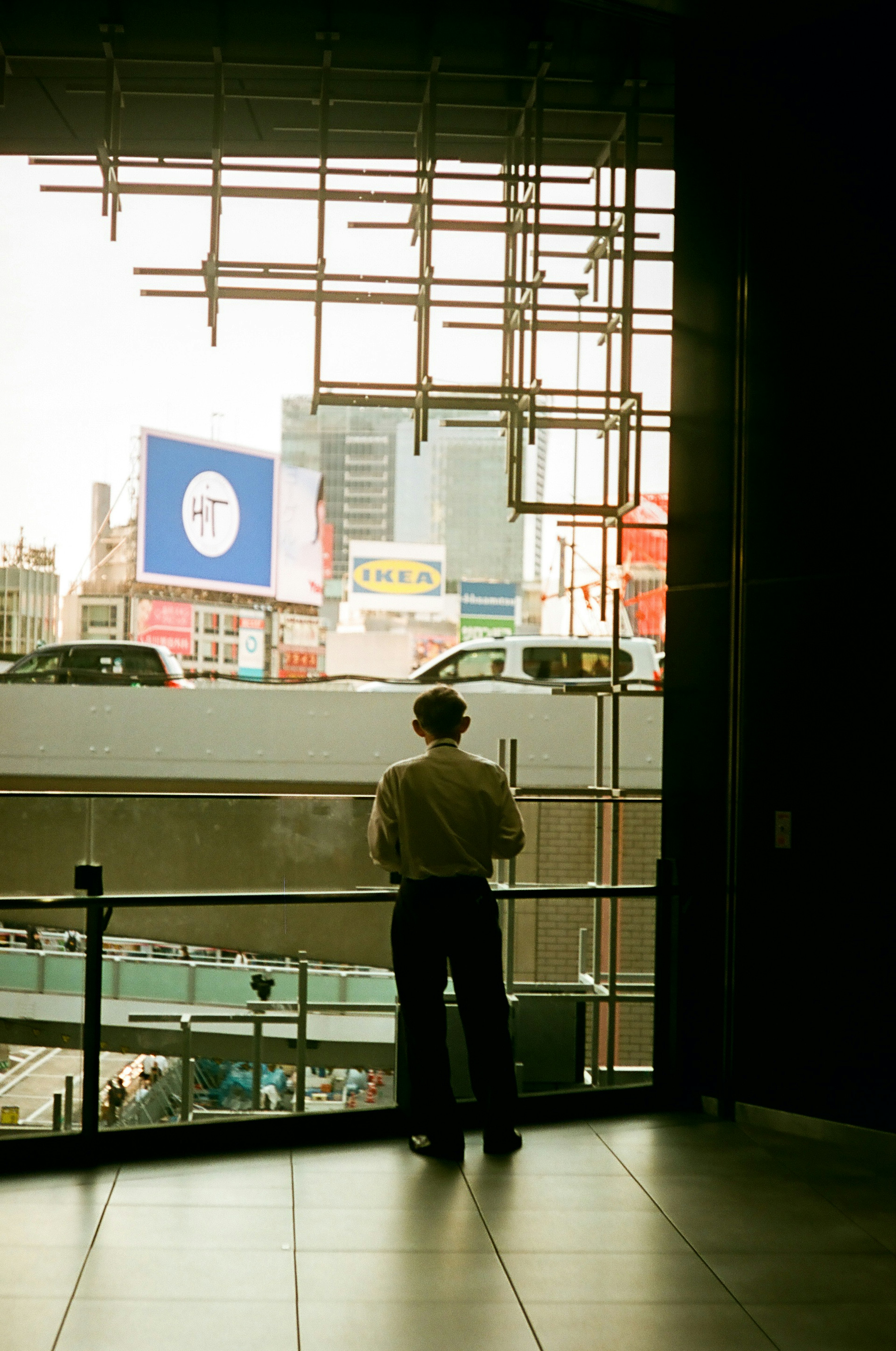 Un hombre de pie junto a una ventana mirando un paisaje urbano