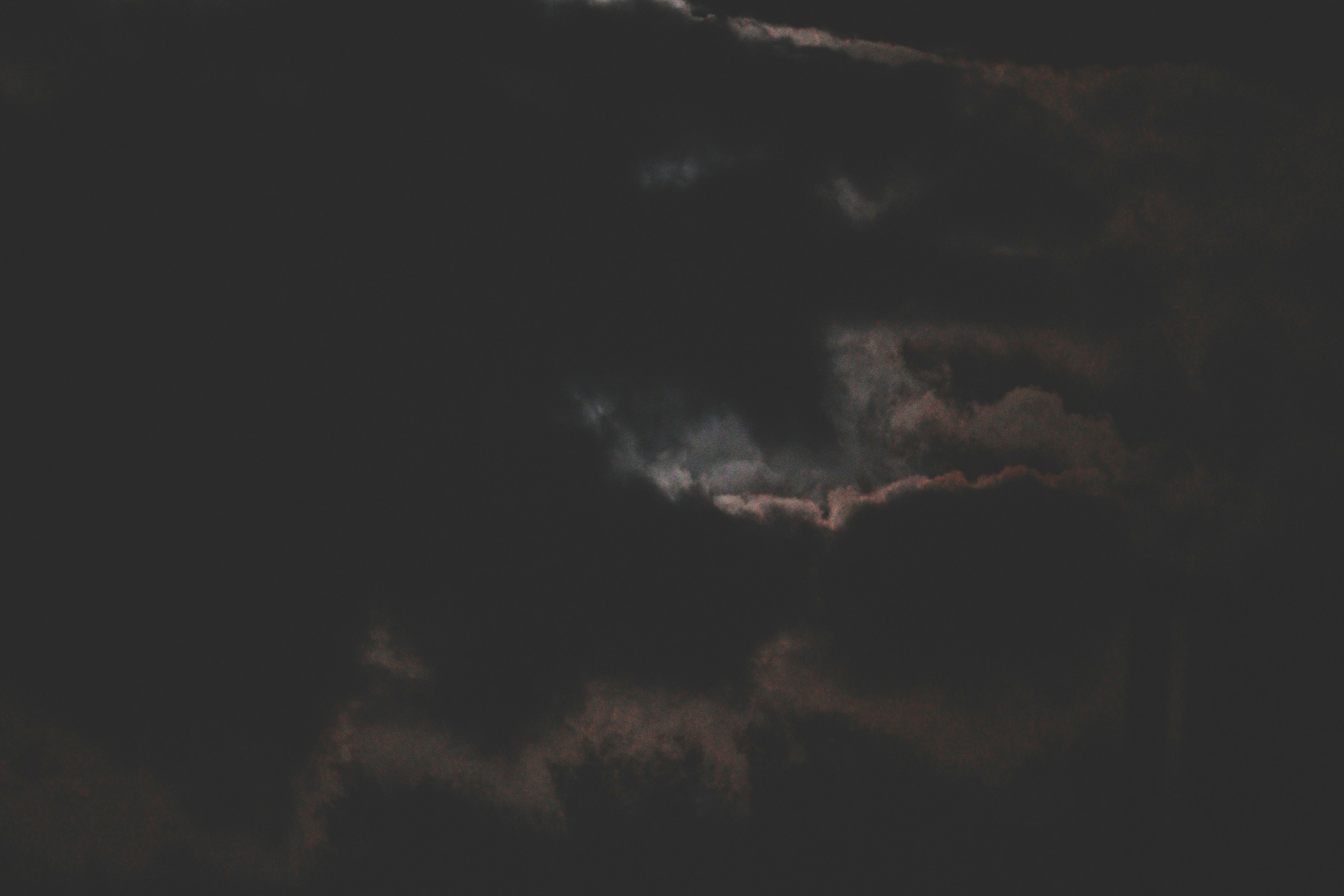 Night sky with dark clouds and a hint of light breaking through