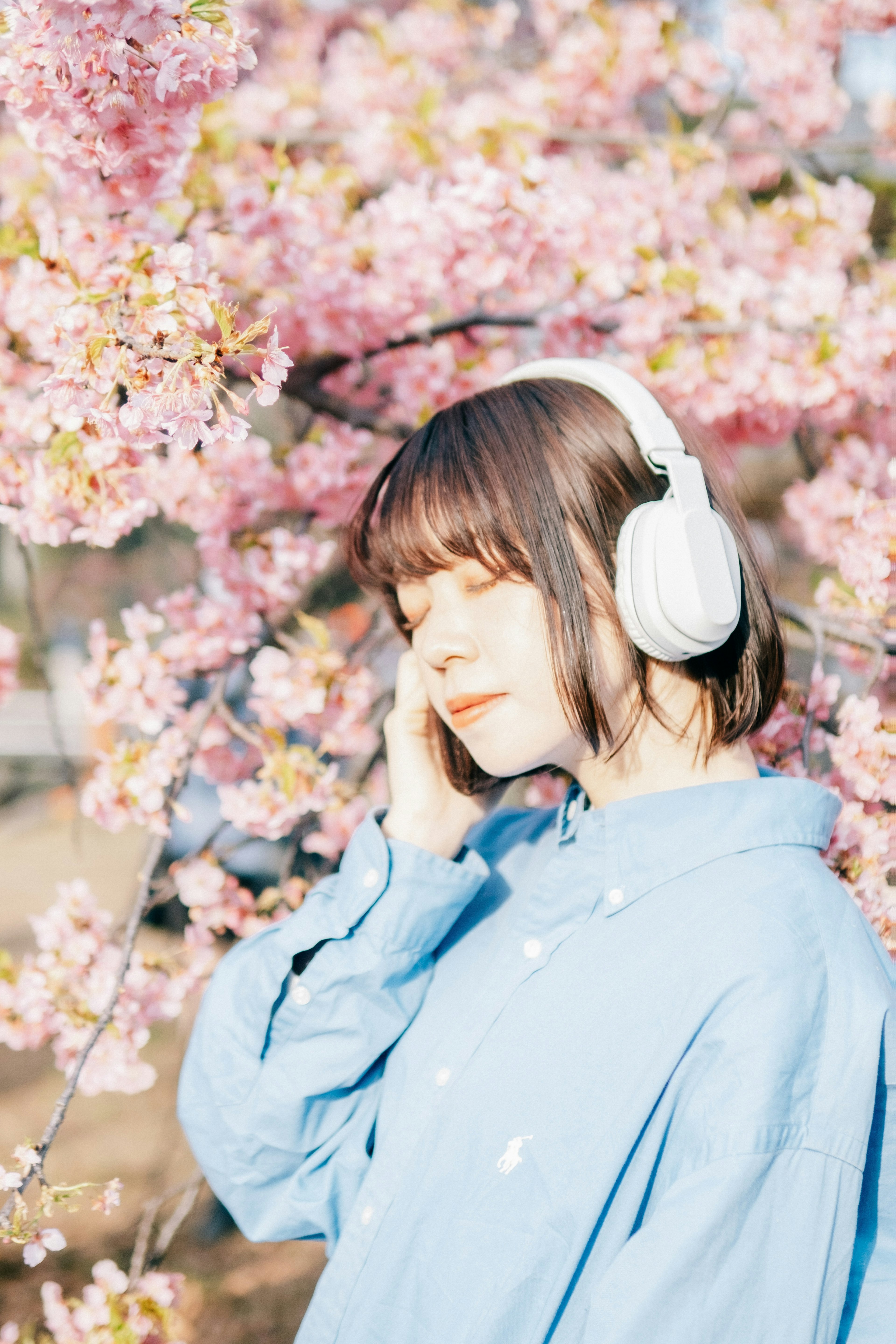 Femme portant des écouteurs devant des cerisiers en fleurs