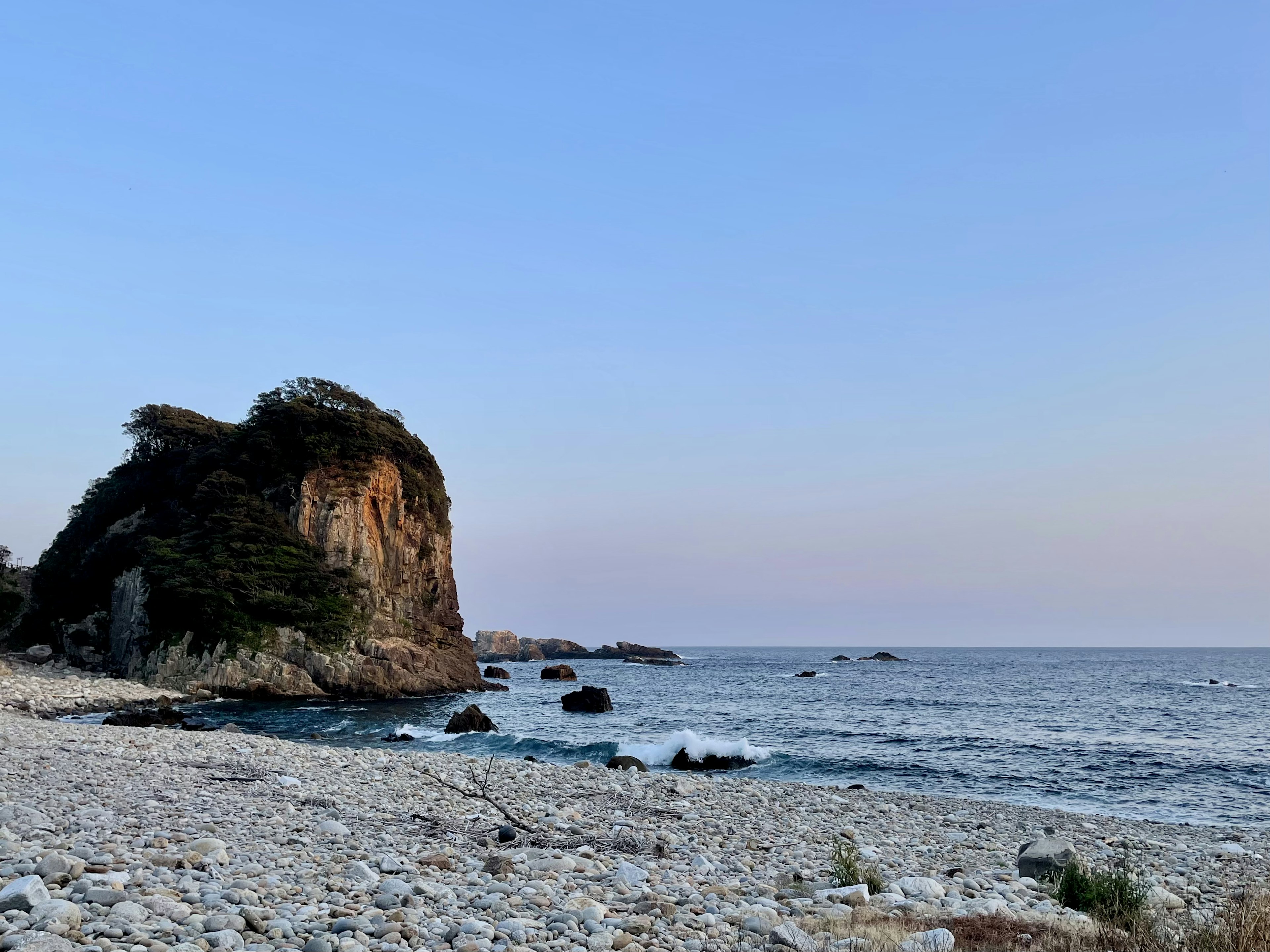 海岸の岩と石のビーチの風景夕暮れの空が広がる