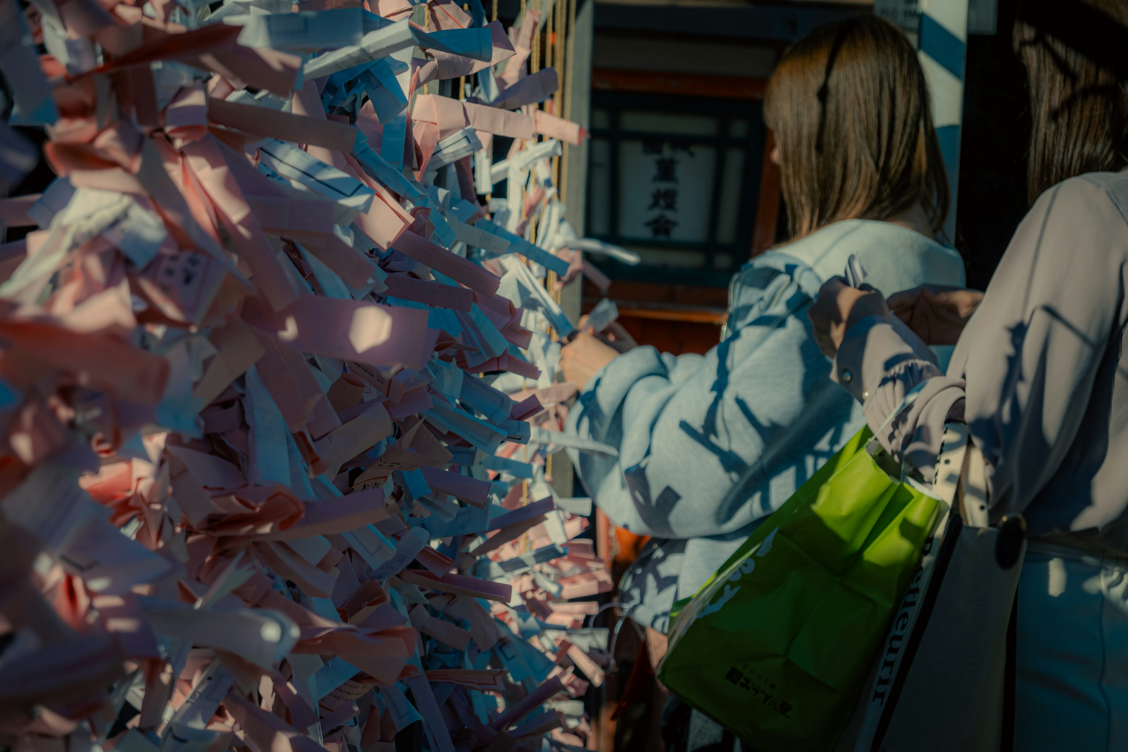 Personas atando fortunes de papel colorido en un santuario