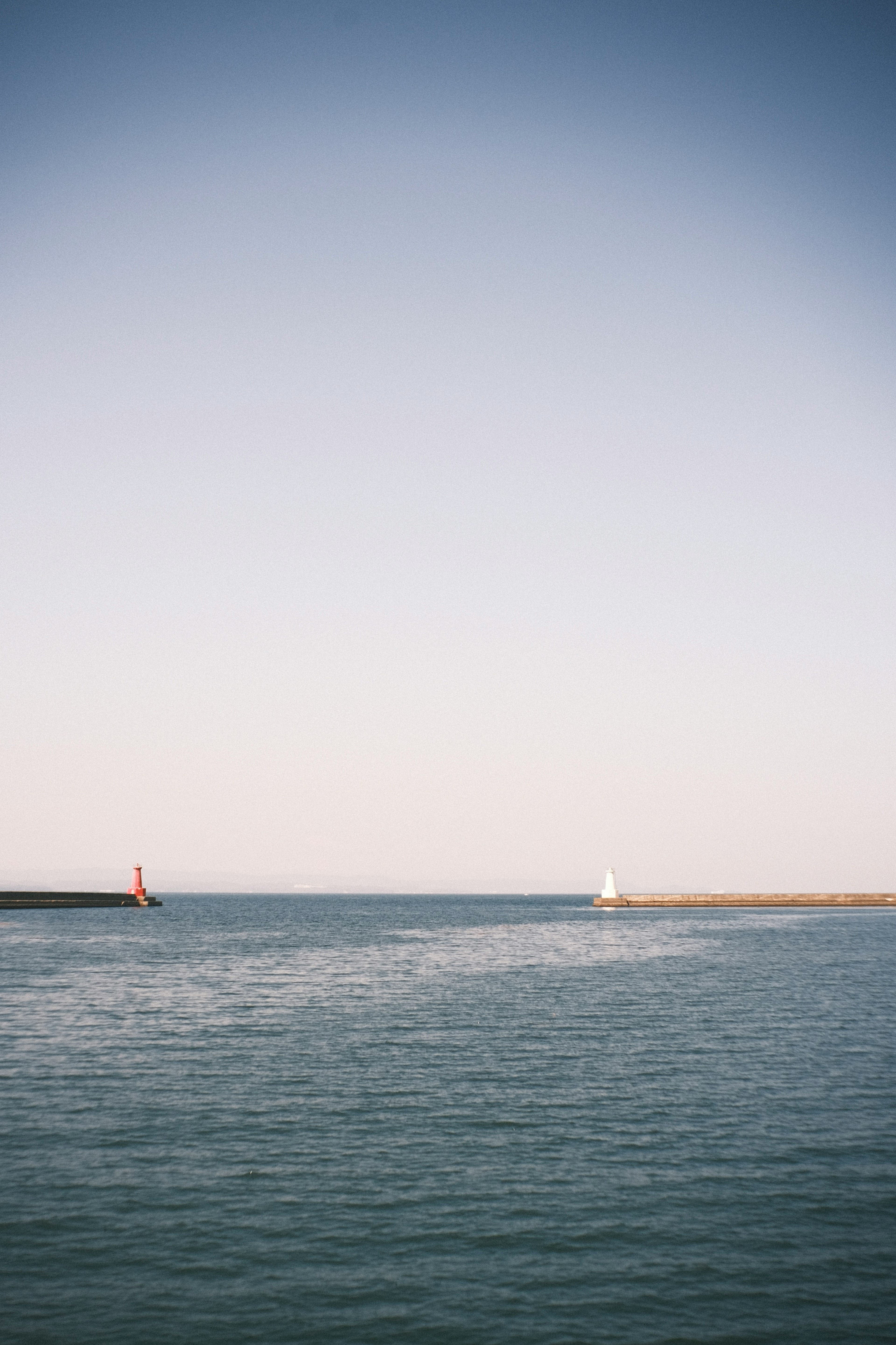 Calm seascape with small lighthouses on a blue water surface