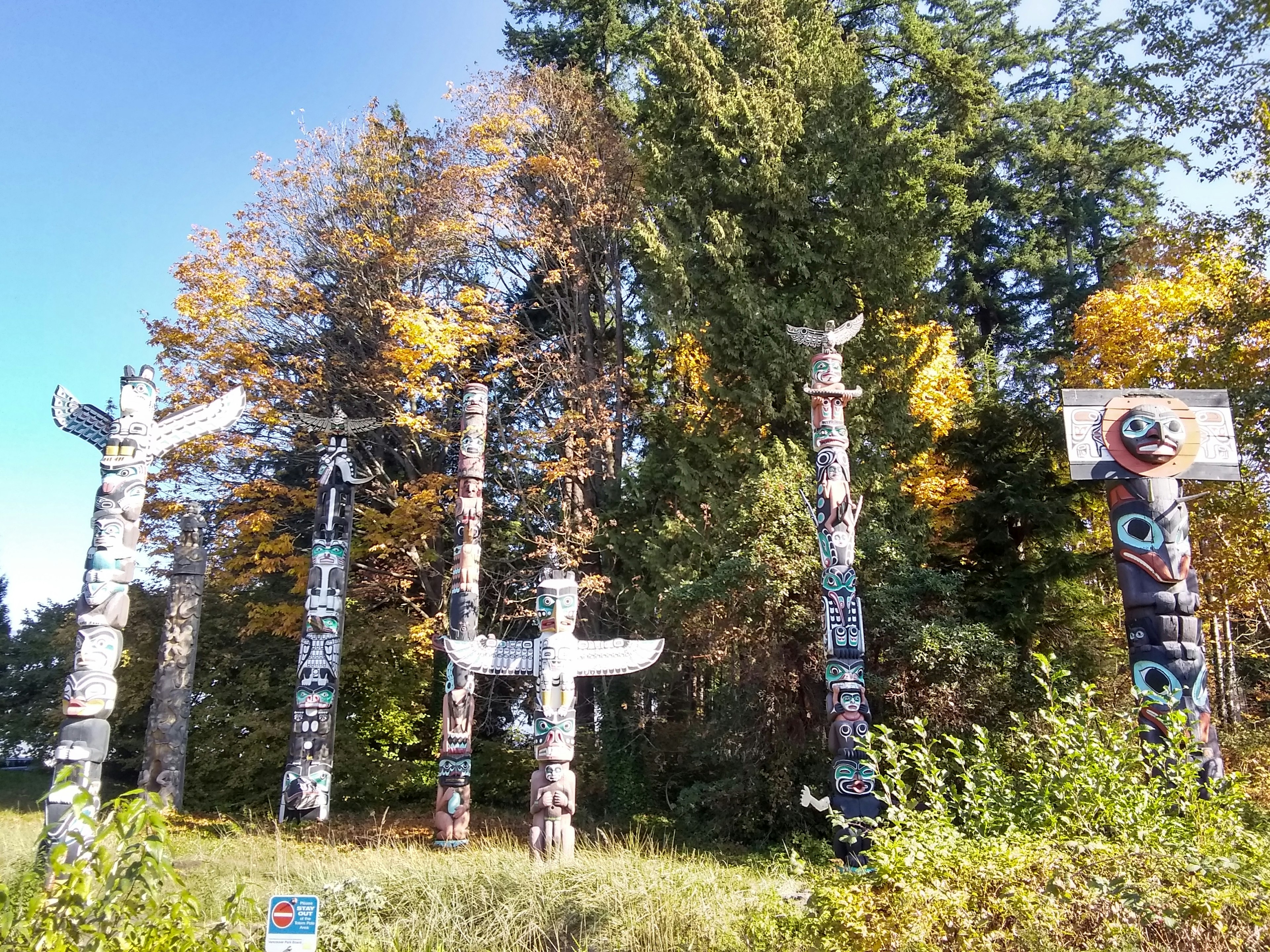 Totempfähle umgeben von lebhaftem Herbstlaub