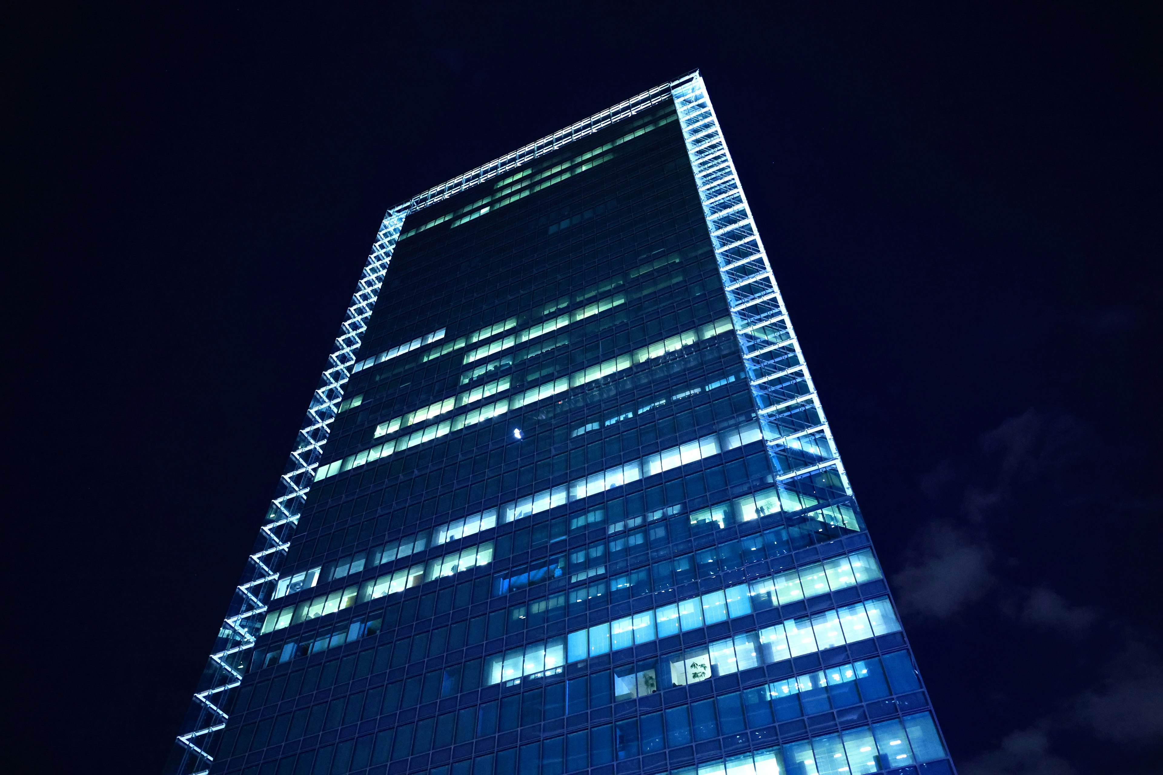 Modern skyscraper illuminated in blue against the night sky