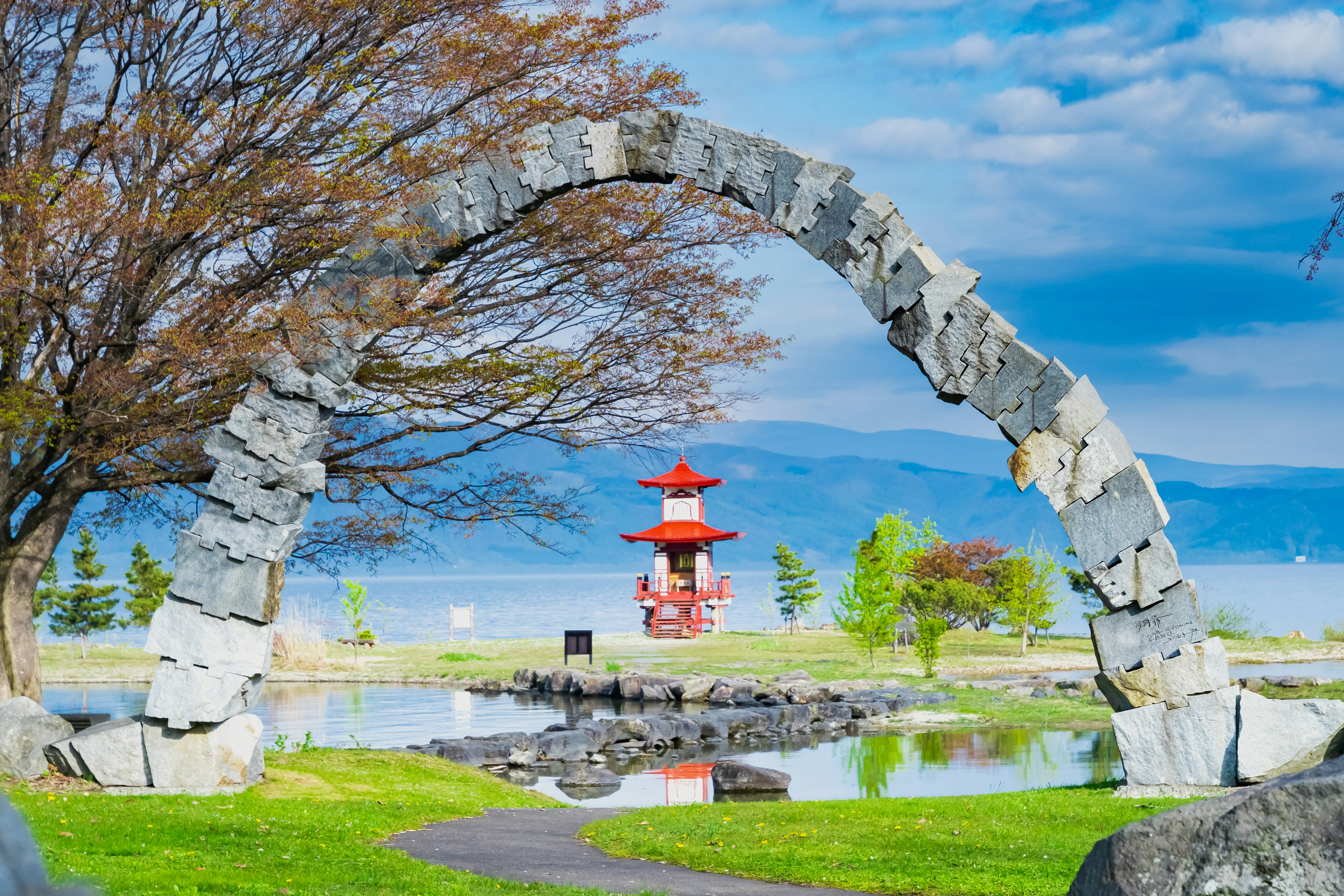 Arco de piedra en un parque con una pagoda roja al fondo