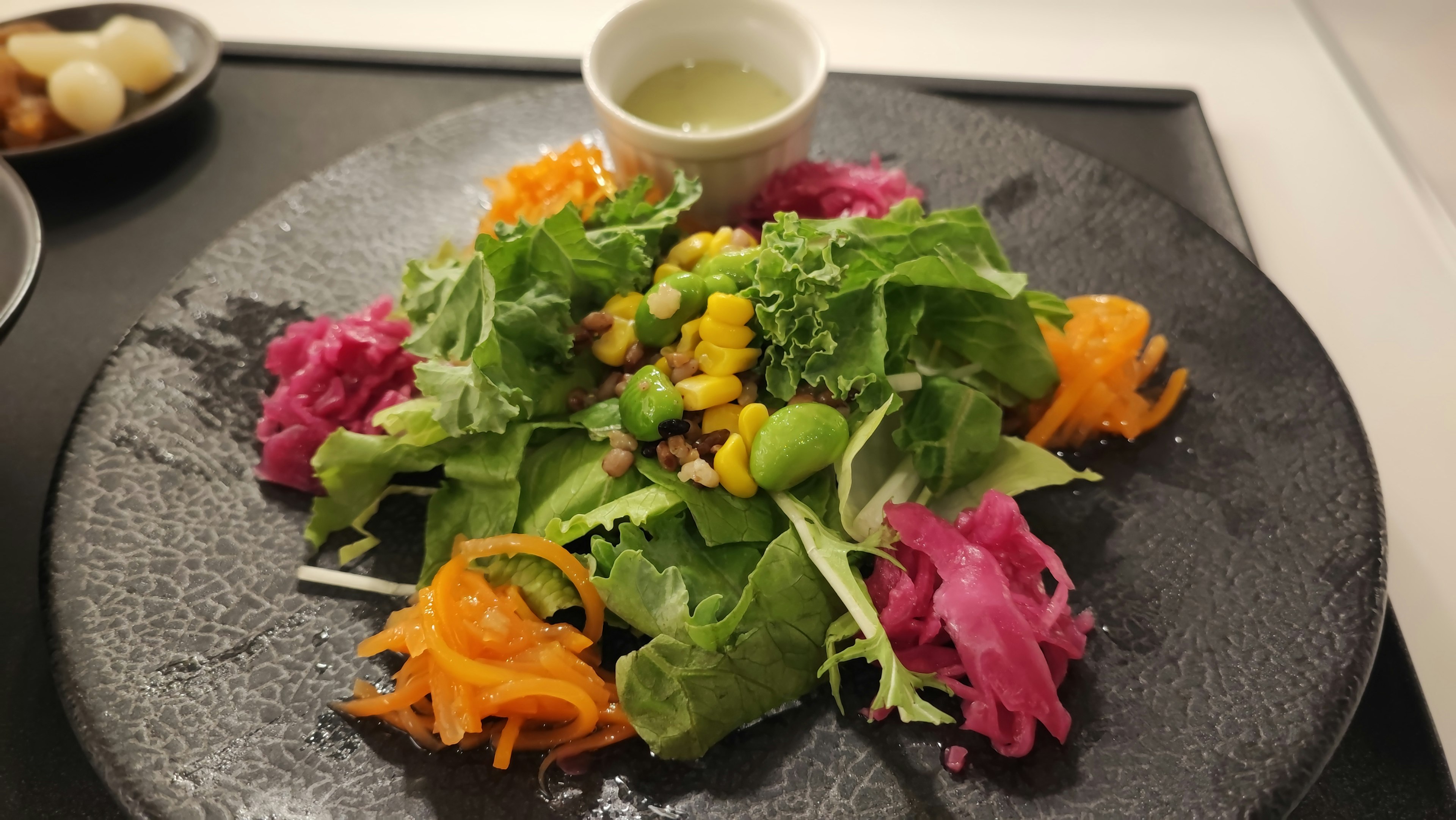 Ensalada colorida con verduras de hoja verde y verduras naranjas y rosas vibrantes en un plato