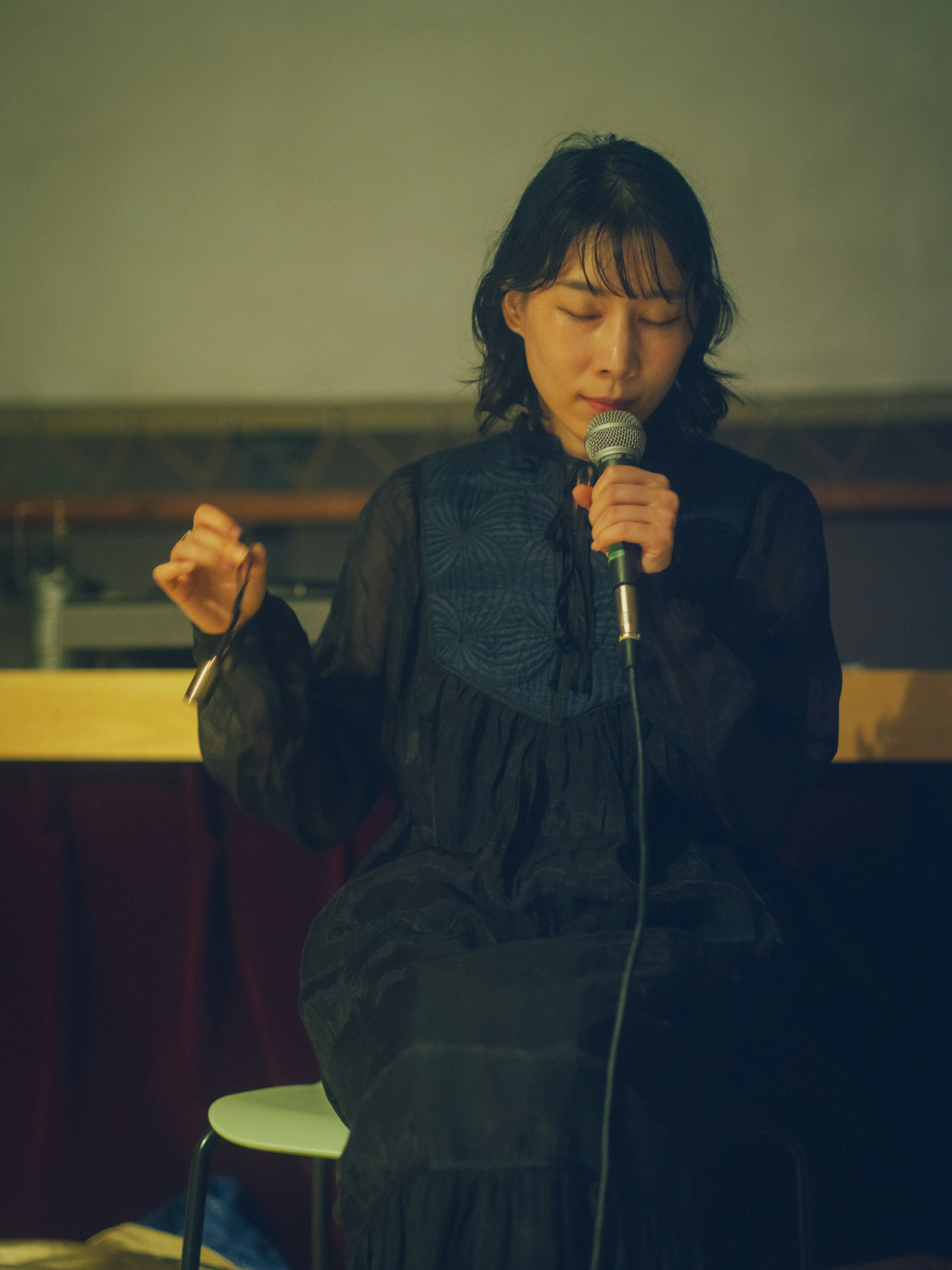 A woman in a black dress speaking into a microphone