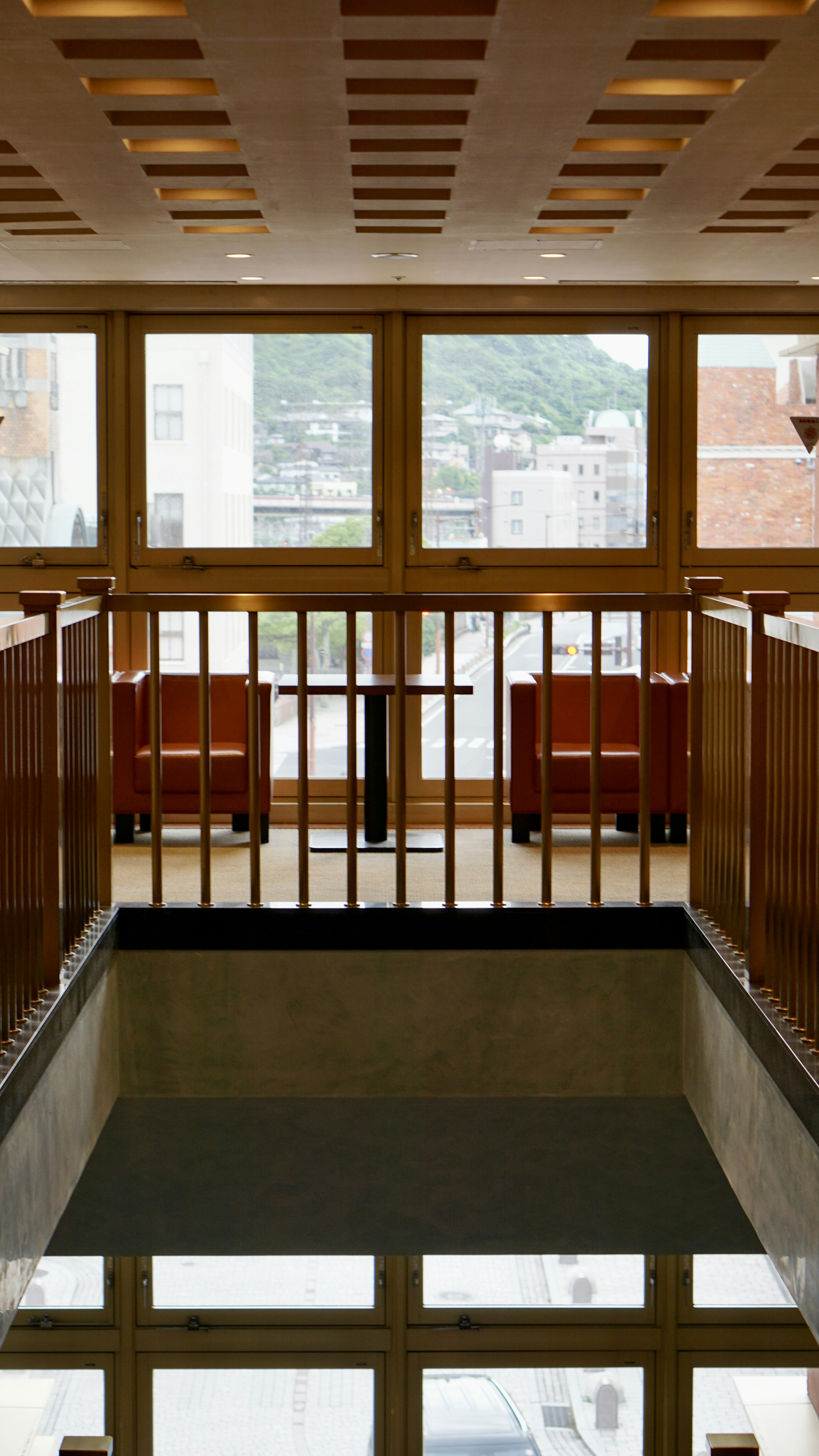 Modern lobby interior with bright windows reflecting floor and wooden balcony