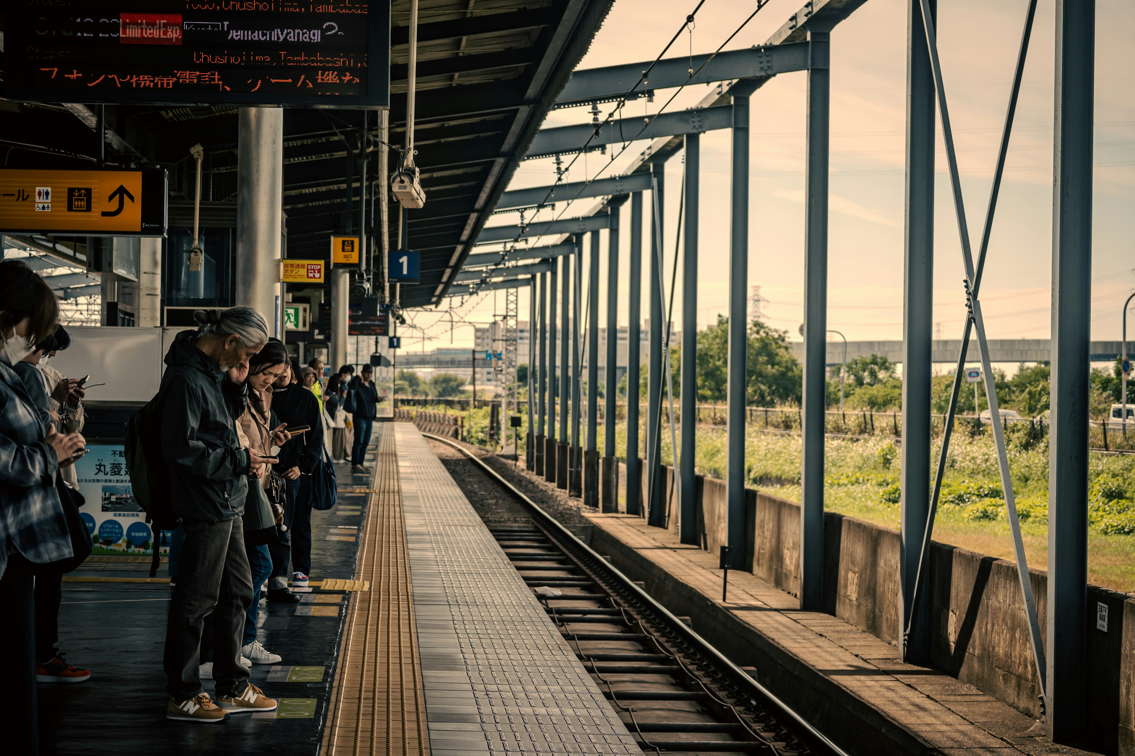 駅で列車を待つ人々と線路が見える風景