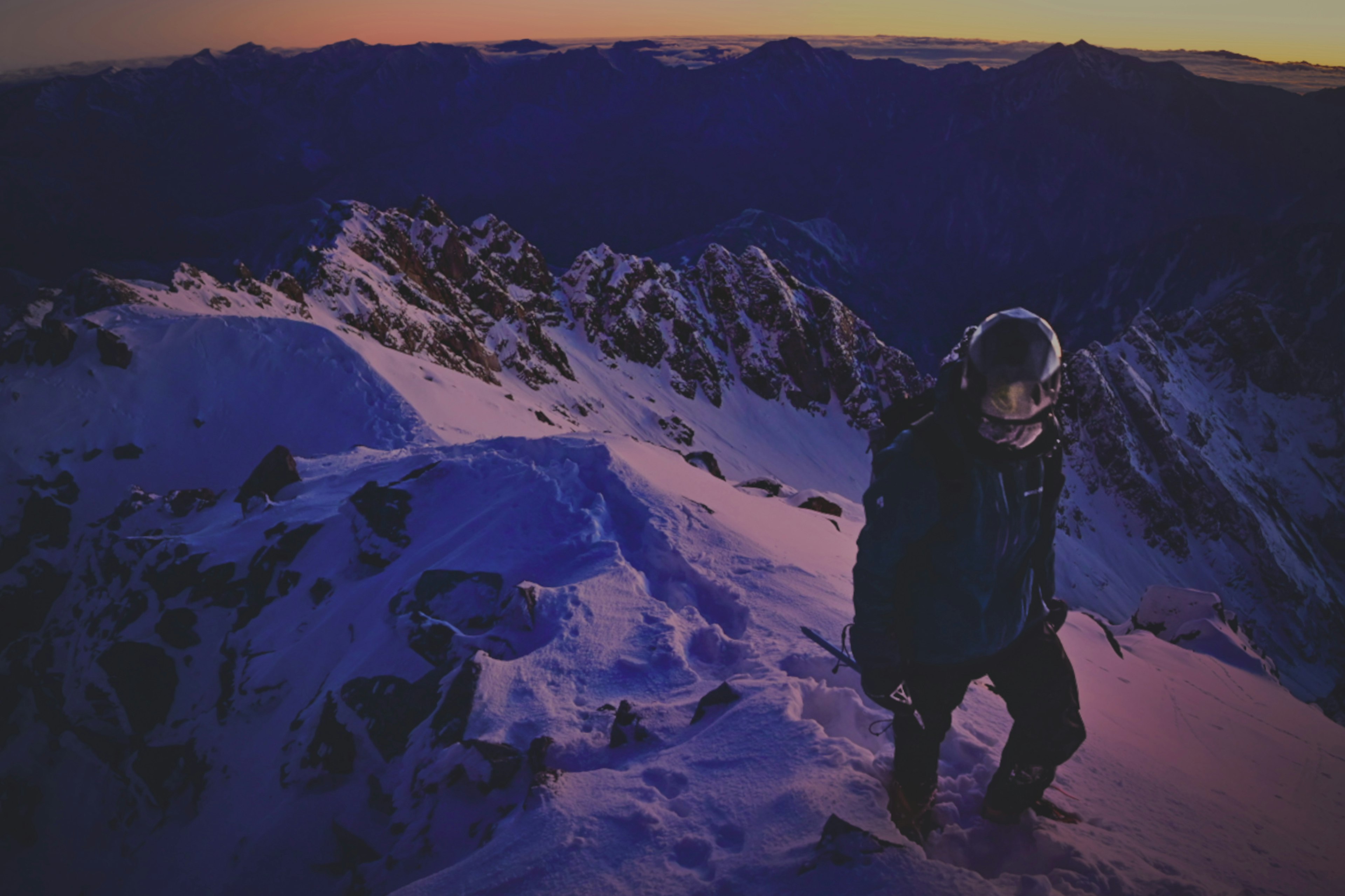 雪山の頂上で登山者が歩いているシーン夕暮れの色合いが美しい